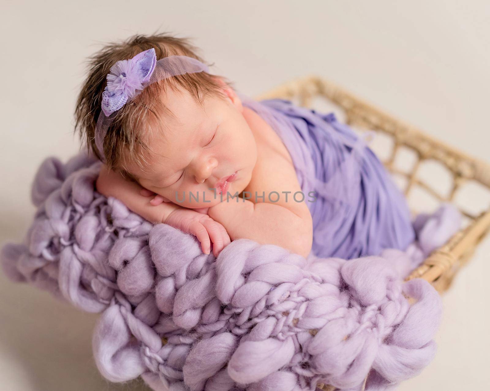 Cute little baby covered with blue coverlet sleeping in the basket