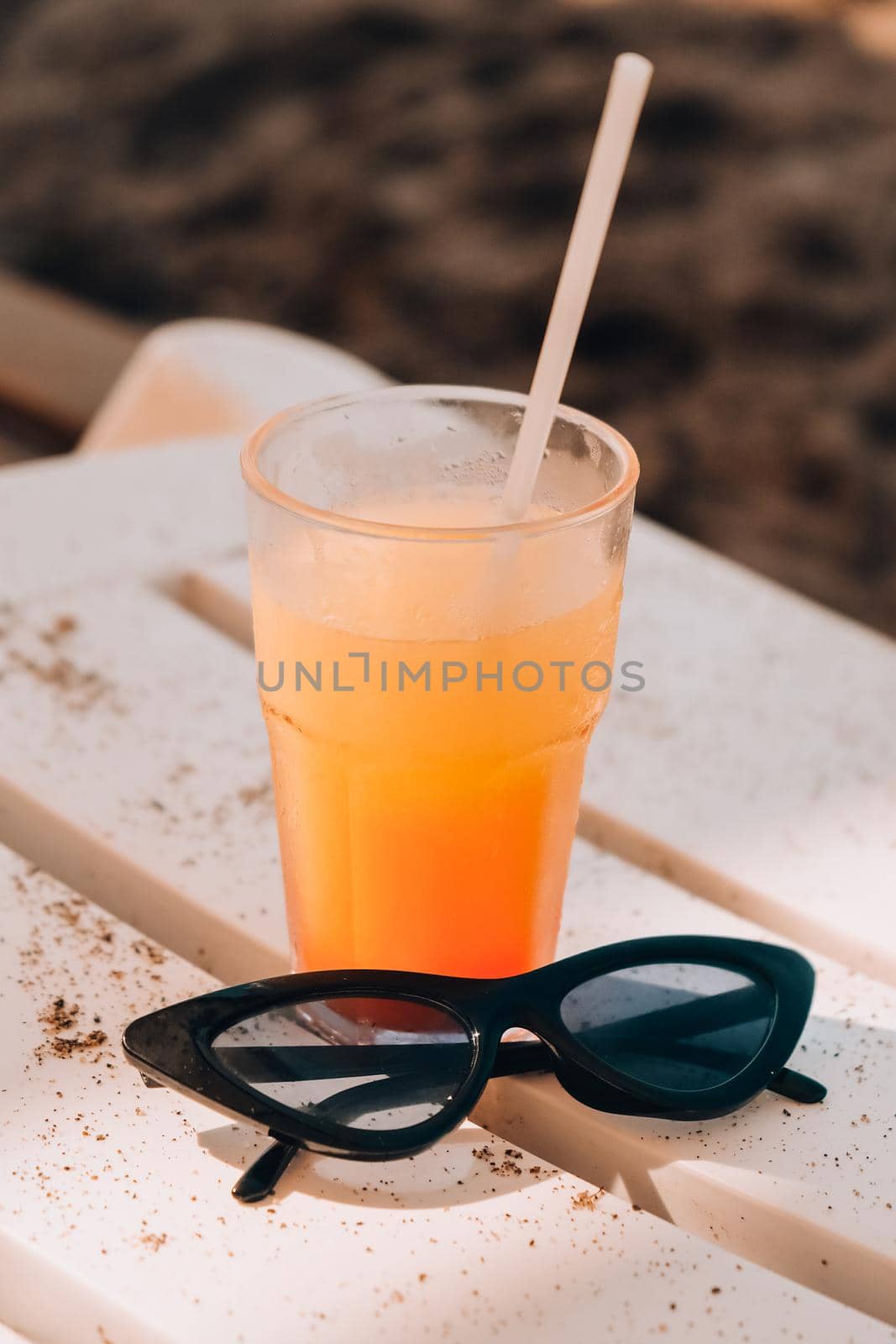 Fresh cold mango smoothie cocktail on tropical beach bright sand. Summer sea vacation and travel concept. Glass of fruit cocktail and sunglasses. Summertime vacation