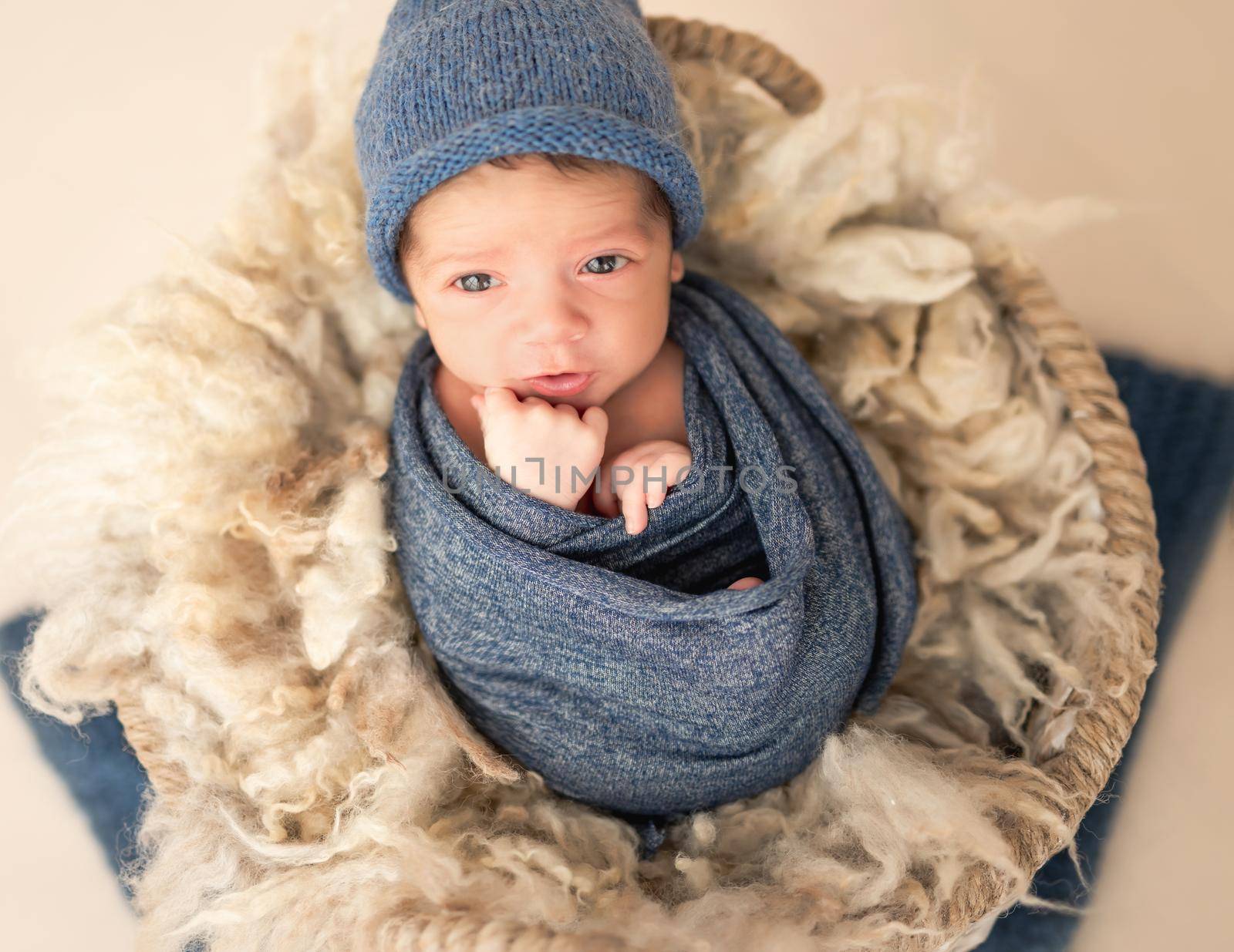 Charming newborn with open eyes lying in cradle