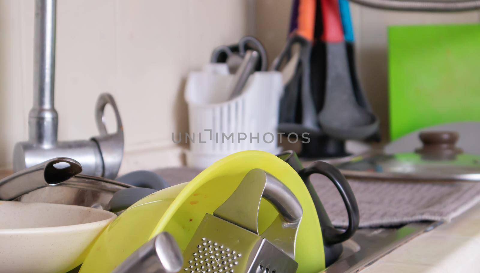 The kitchen utensils in the wash basin need to be washed. A pile of dirty dishes in the kitchen sink. Kitchen utensils need washing. Homework concept