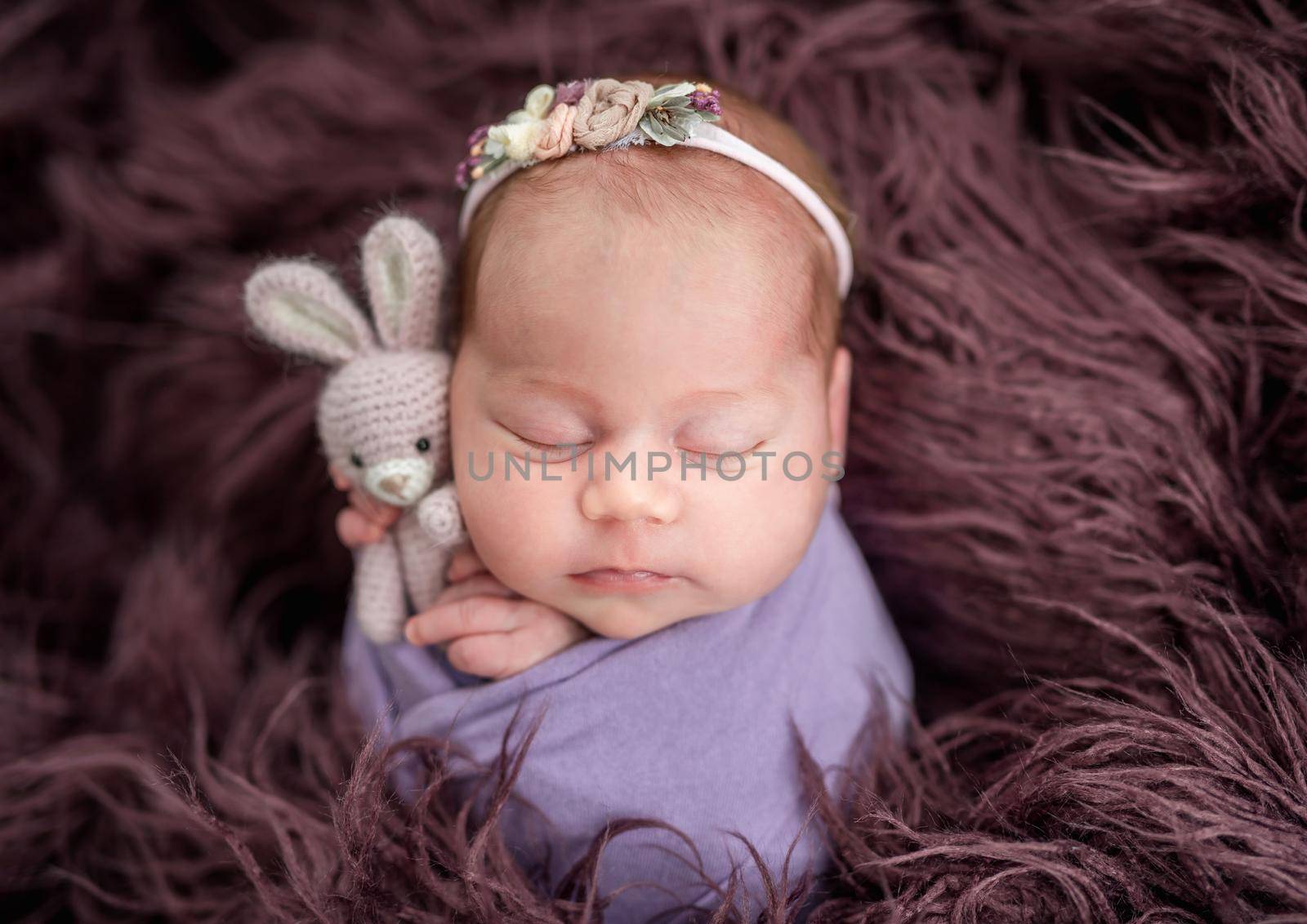Lovely newborn holding toy in tiny hands
