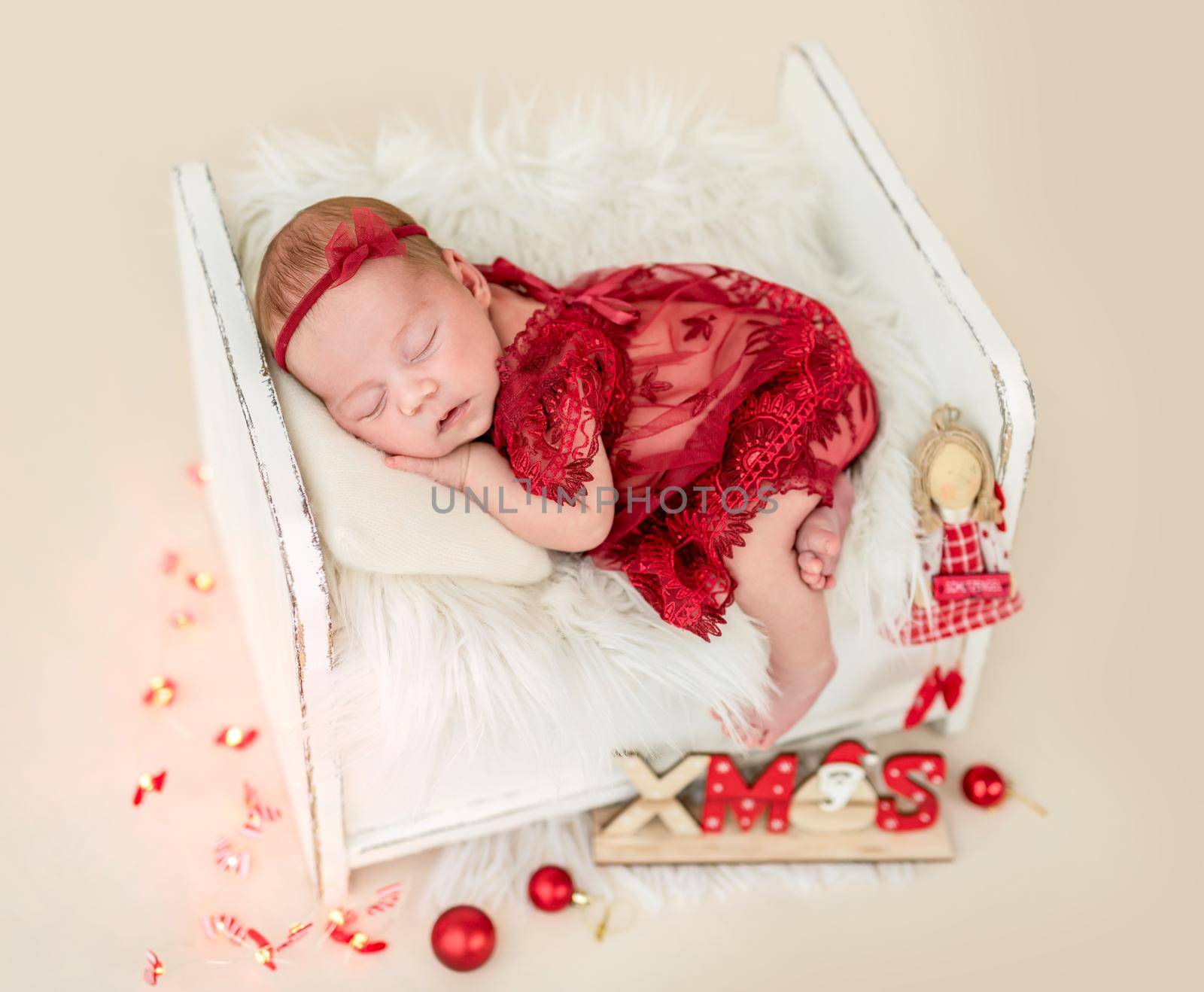 Dreaming newborn in tiny bed with christmas decorations
