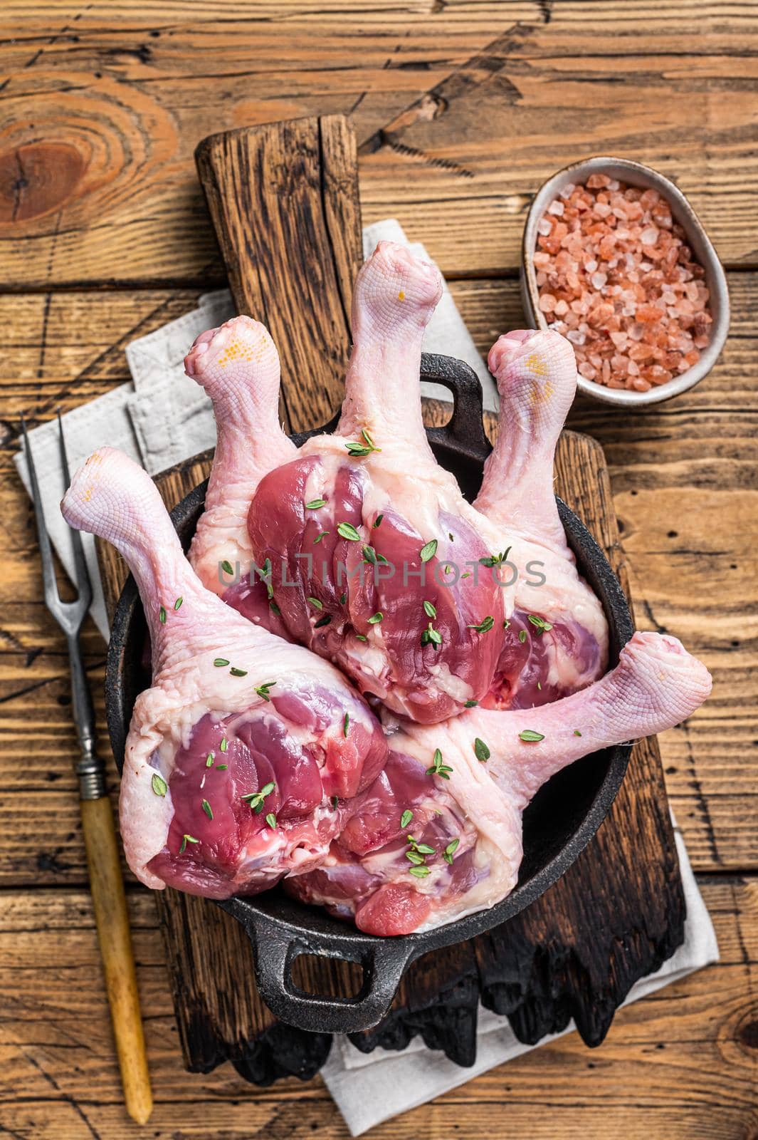 Raw Duck drumsticks in a pan with herbs. wooden background. Top view by Composter