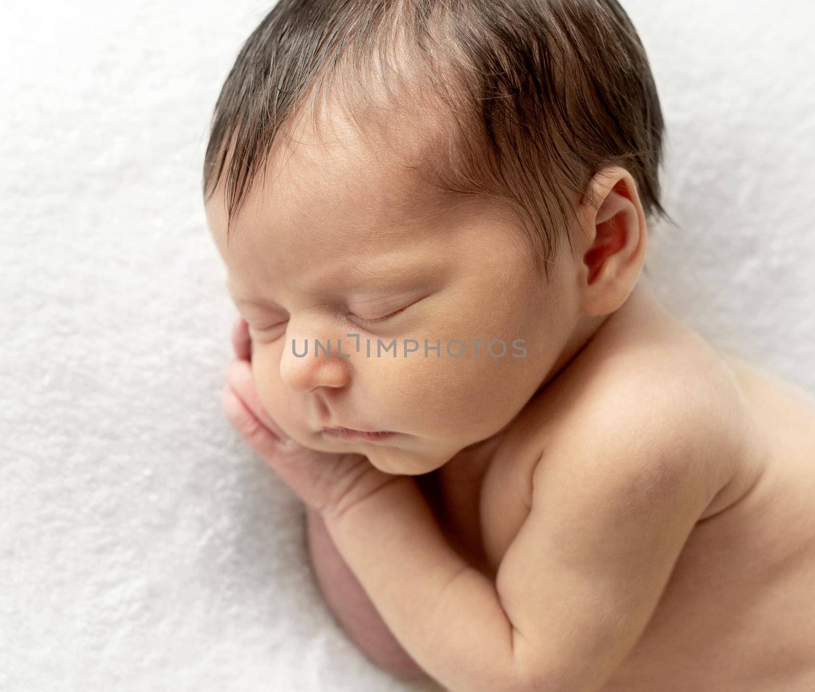 Just a few days old baby sleeping on tummy. Sleeping newborn child curled up. Beginning of a new life concept