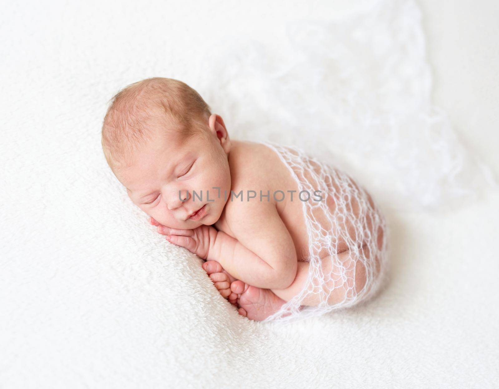 A sleeping baby boy on lace fabric, isolated on white background