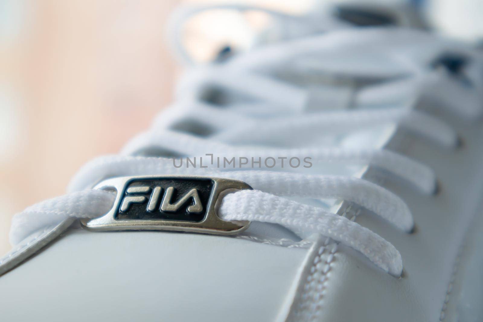 White athletic lace-up sneakers. White laces are tied close-up. Blurred background. Sports concept. Famous brand logo Fila. Fashionable and stylish footwear. Ukraine, Kiev - June 17, 2021