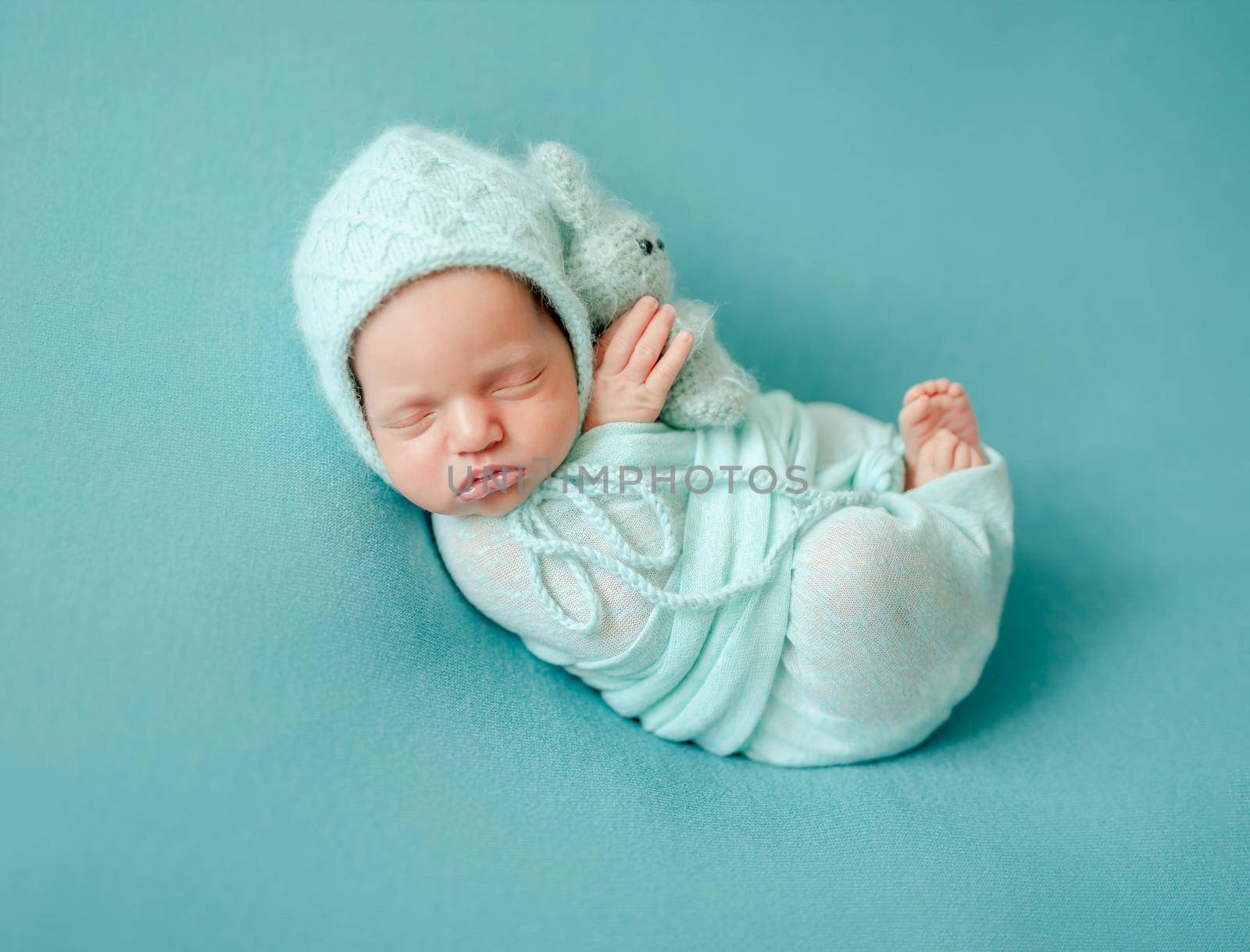 Little newborn wrapped in blue blanket resting in room