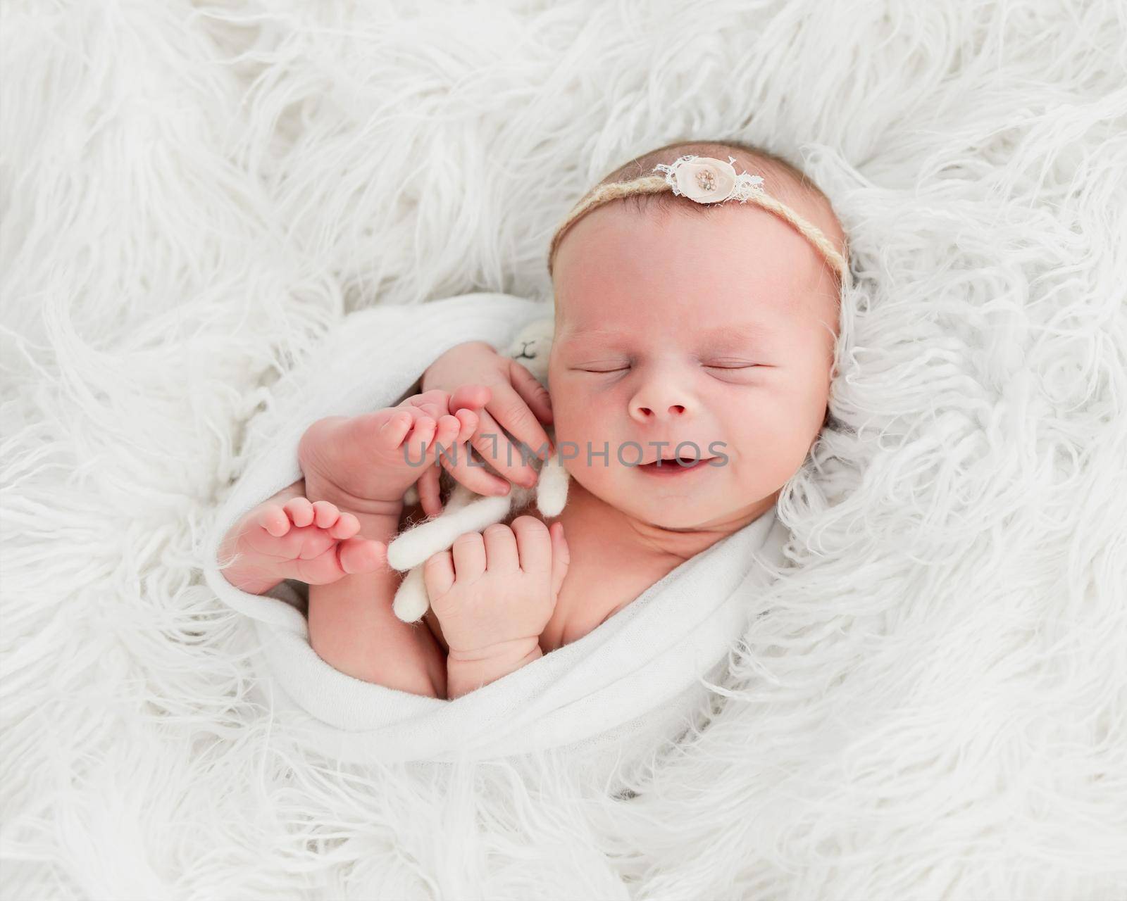 smiling newborn baby girl sleeping sweetly with a small toy