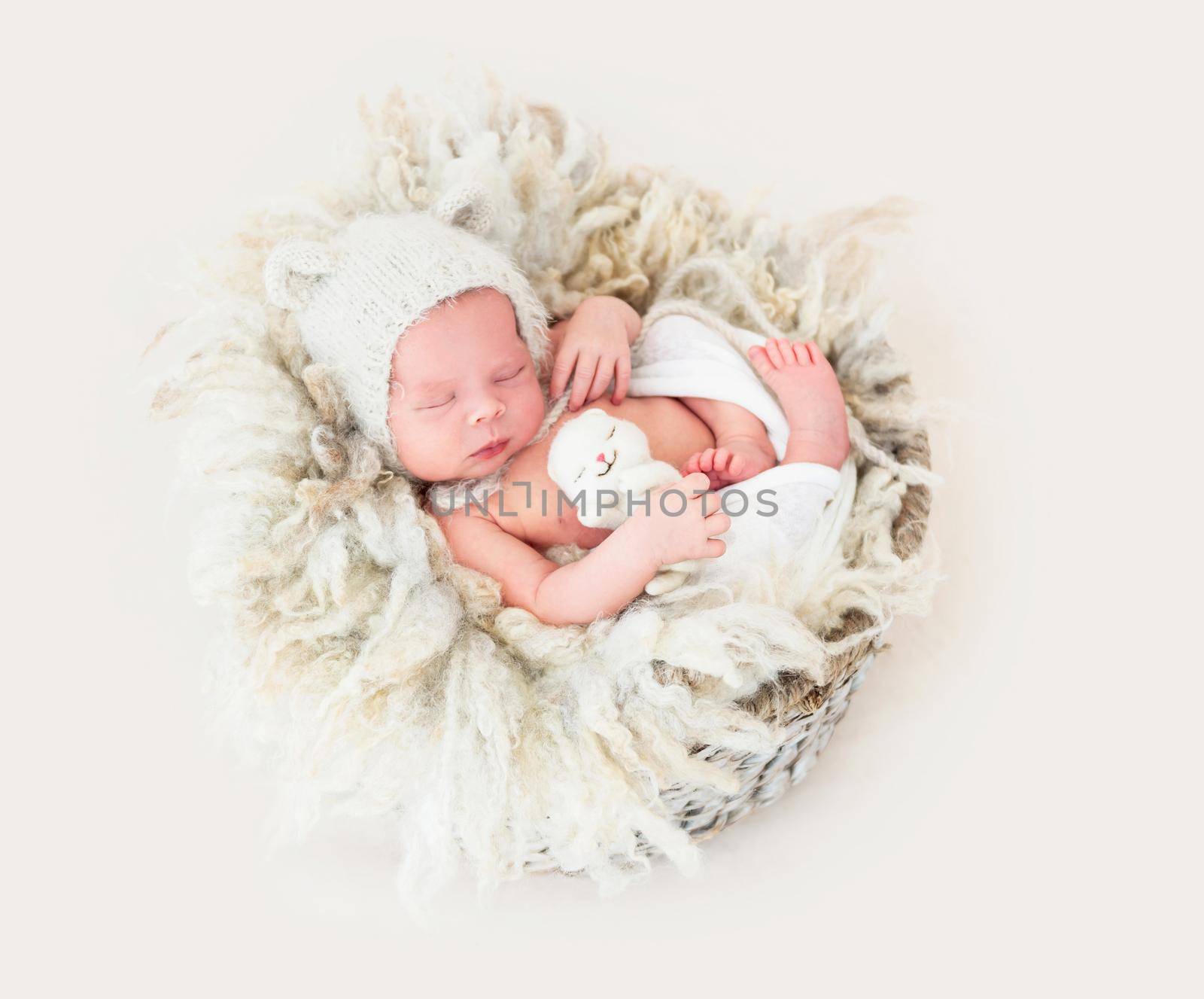 newborn baby girl sleeping sweetly in the basket with a small toy