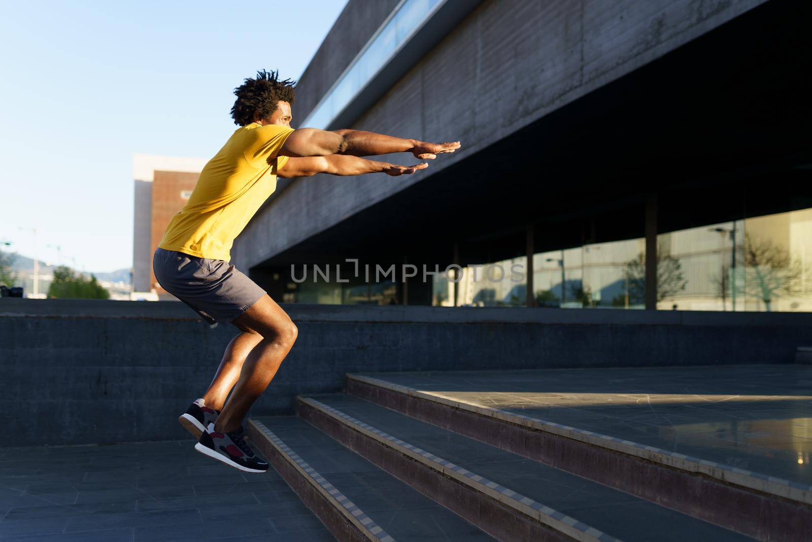 Black man doing squats with jumping on a step as a workout for his legs.