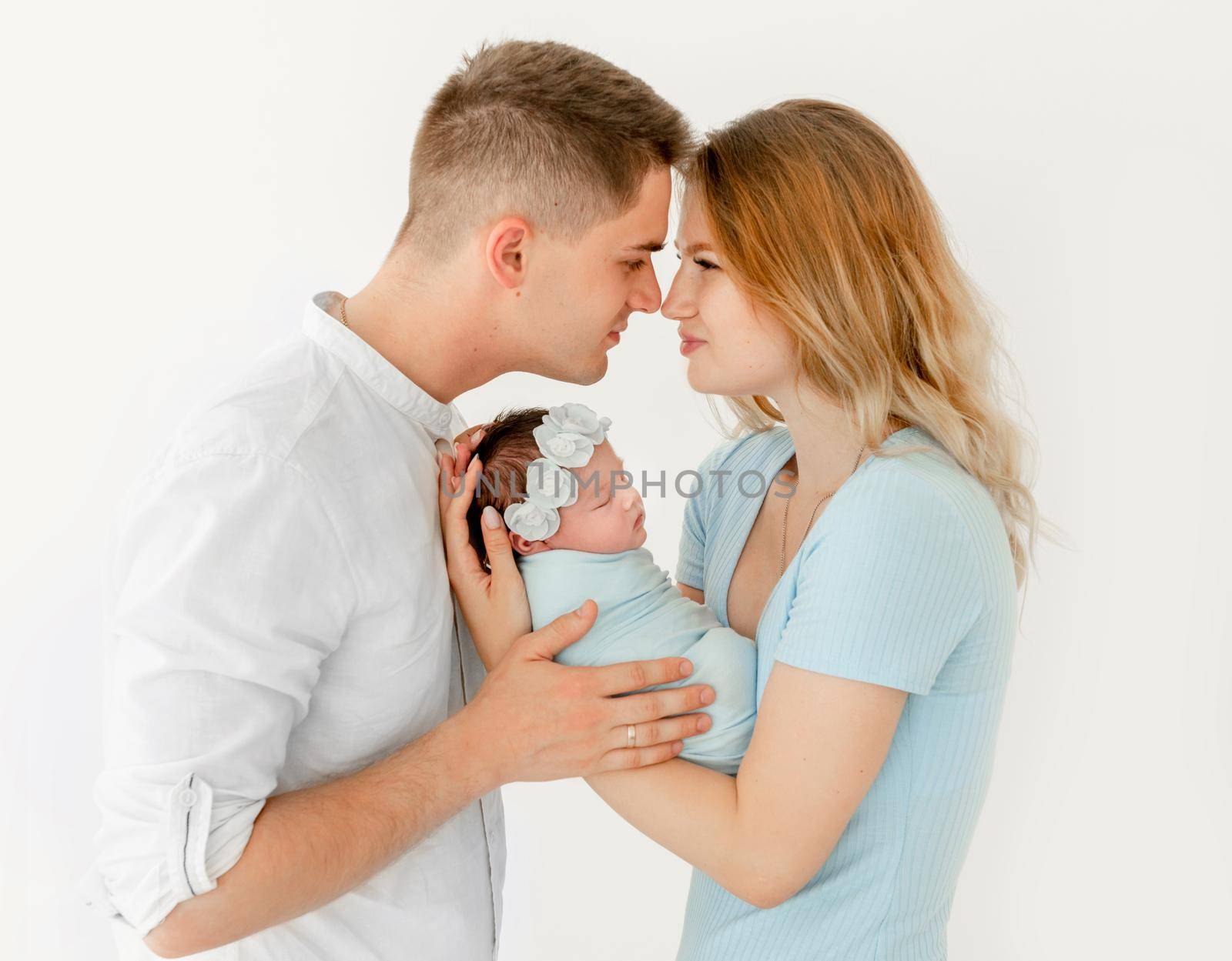young beautiful parents holding a newborn daughter. white background