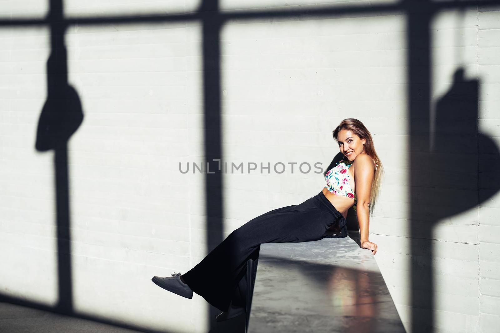 Funny young girl sitting on urban wall outdoors