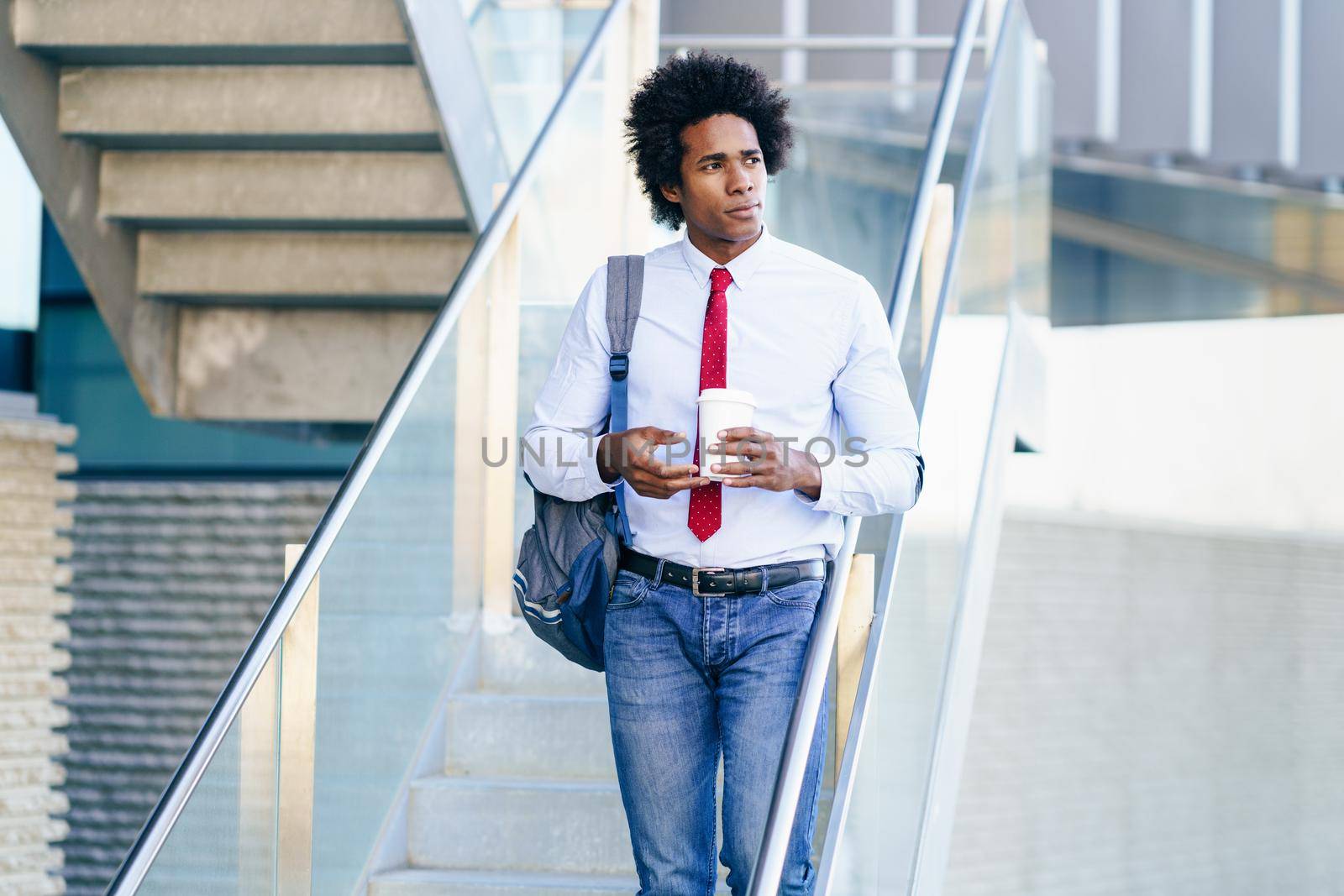 Black Businessman taking a coffee break with a take-away glass. Man with afro hair.