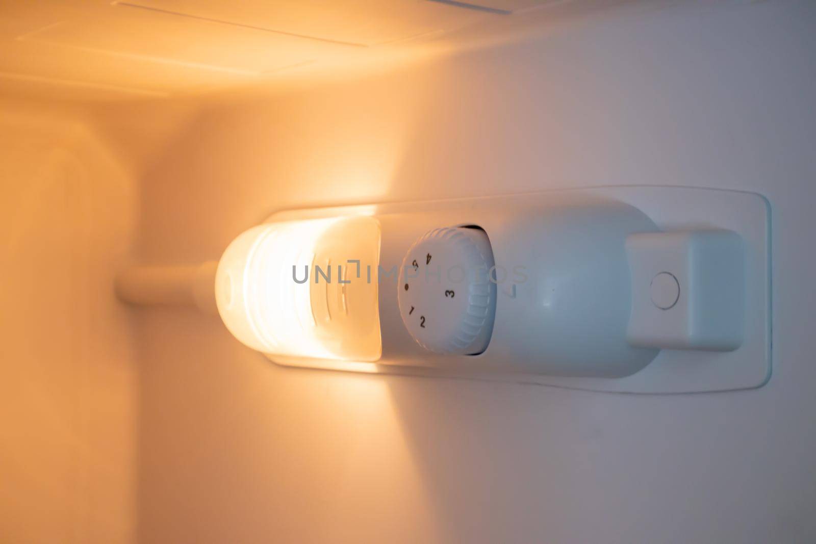 Orange light inside the refrigerator close-up. A lamp that turns on when the door is open to improve vision. Household appliances concept, changing the lamp in the freezer