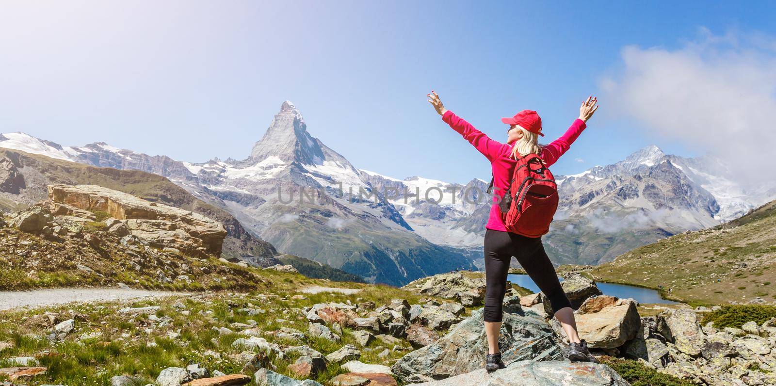 Woman on mountain top of mountain landscape around lake and blue sky