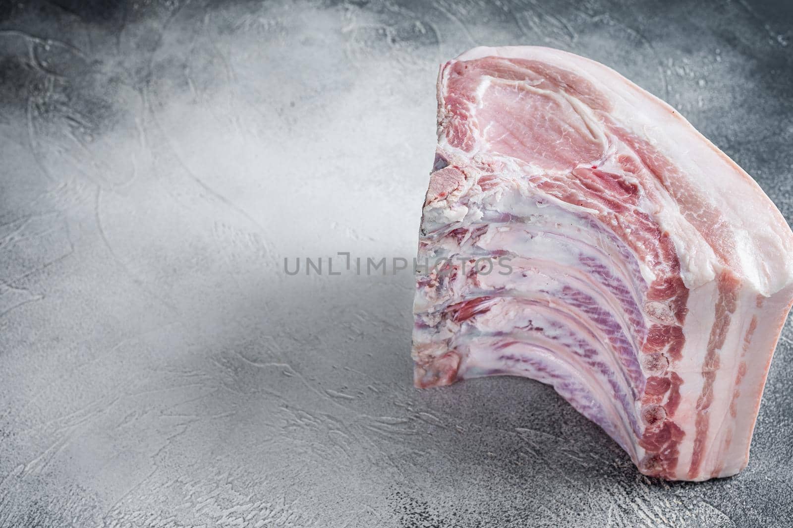 Raw whole rack of pork loin with ribs on kitchen table. White background. Top view. Copy space by Composter