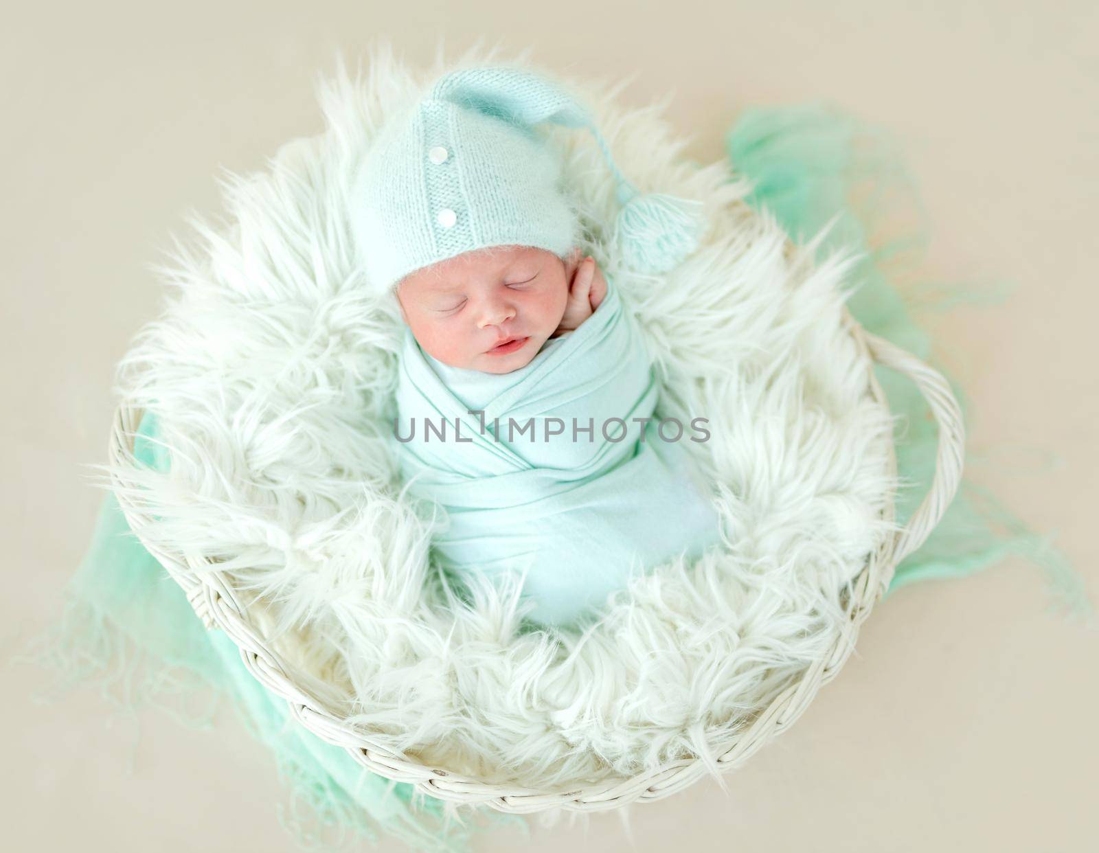 Healthy happy beatiful newborn kid sleeping in child basket, covered in fur