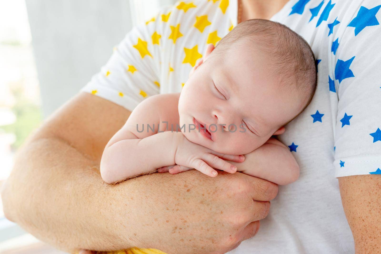 Strong daddy holding naked newborn baby , holding his hand on babys stomach