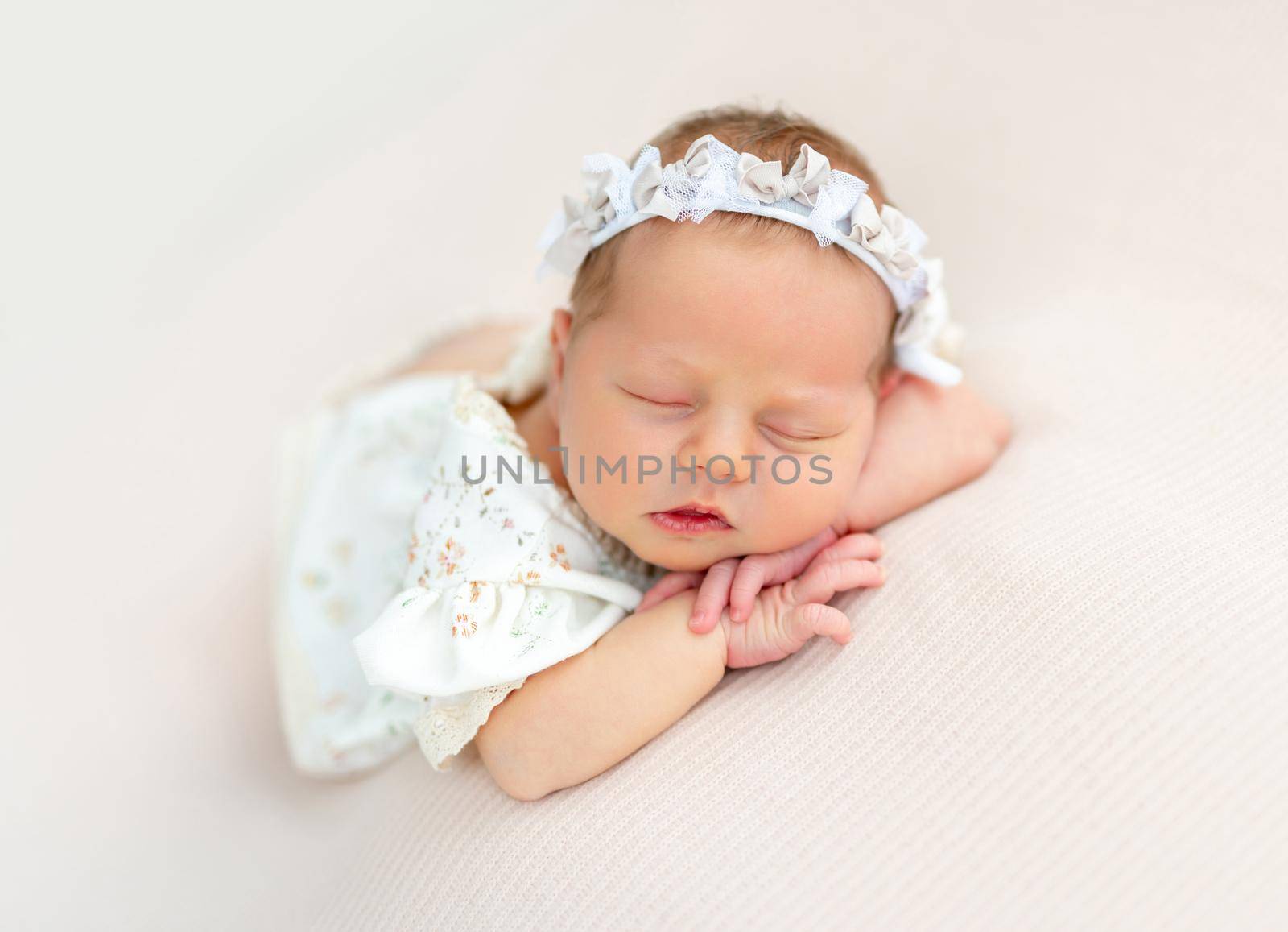 Nice newborn baby resting on stomach with head on hands