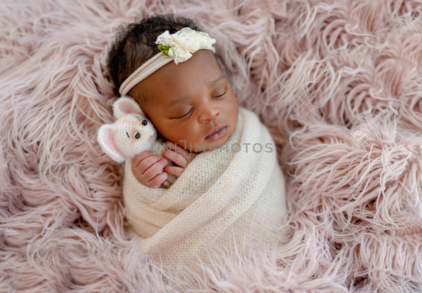 Cute African newborn baby hugging mice toy