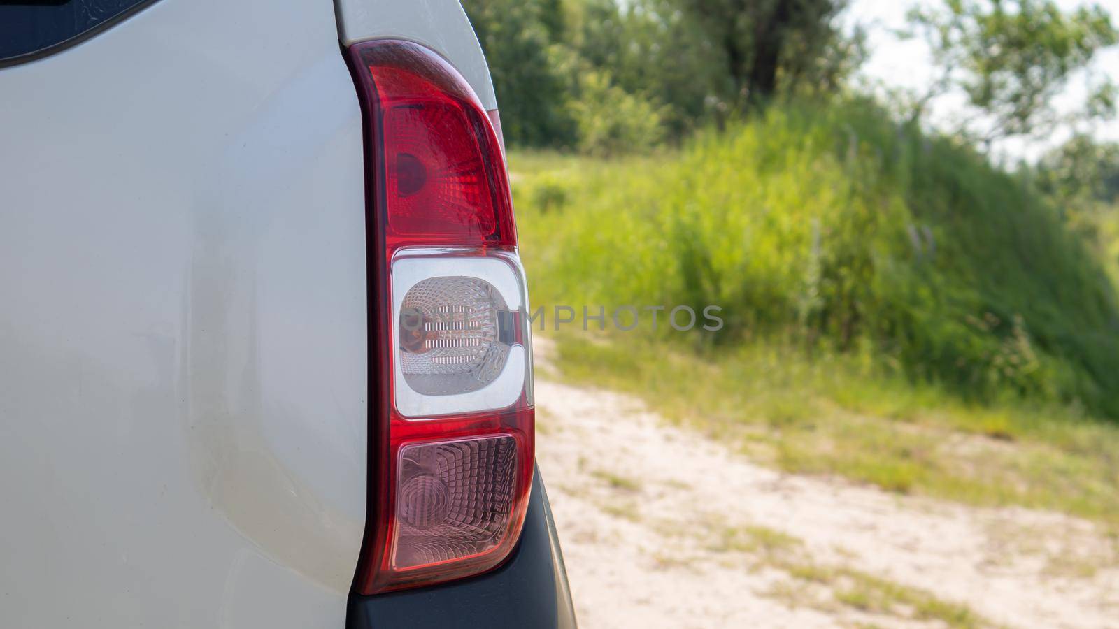 Right rear headlight. The rear of a small passenger hatchback or SUV of a white car with a group of taillights and a part of the trunk lid on the right. Red turn signal and brake light