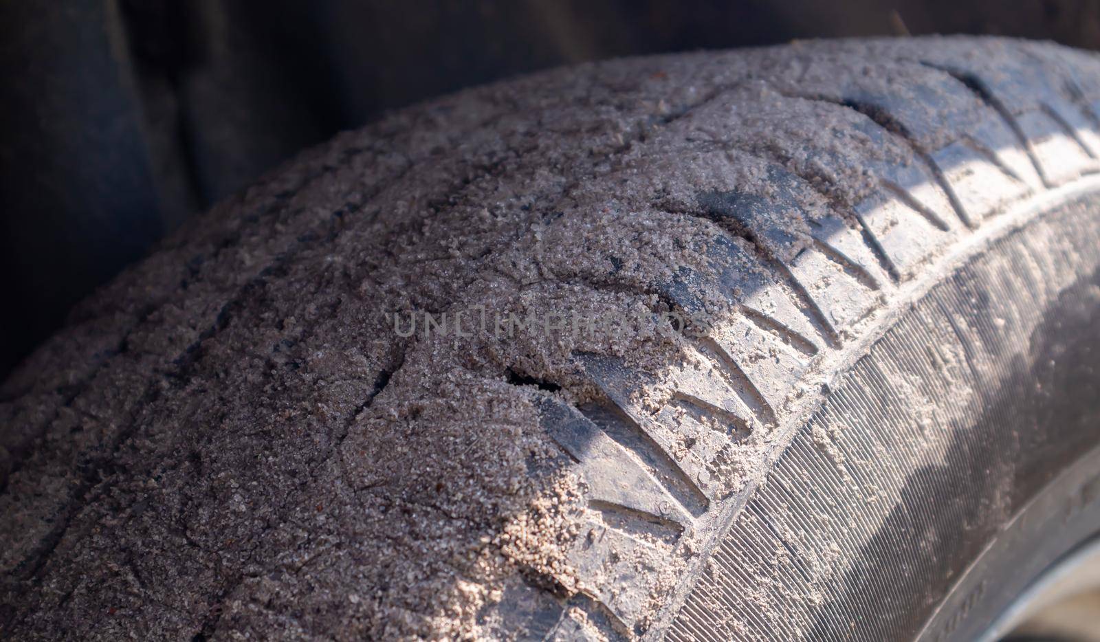 Dirty car wheel on a soil road to the countryside. Close-up detail of a tire. Transport, driving and car concept. The car got stuck in the sand