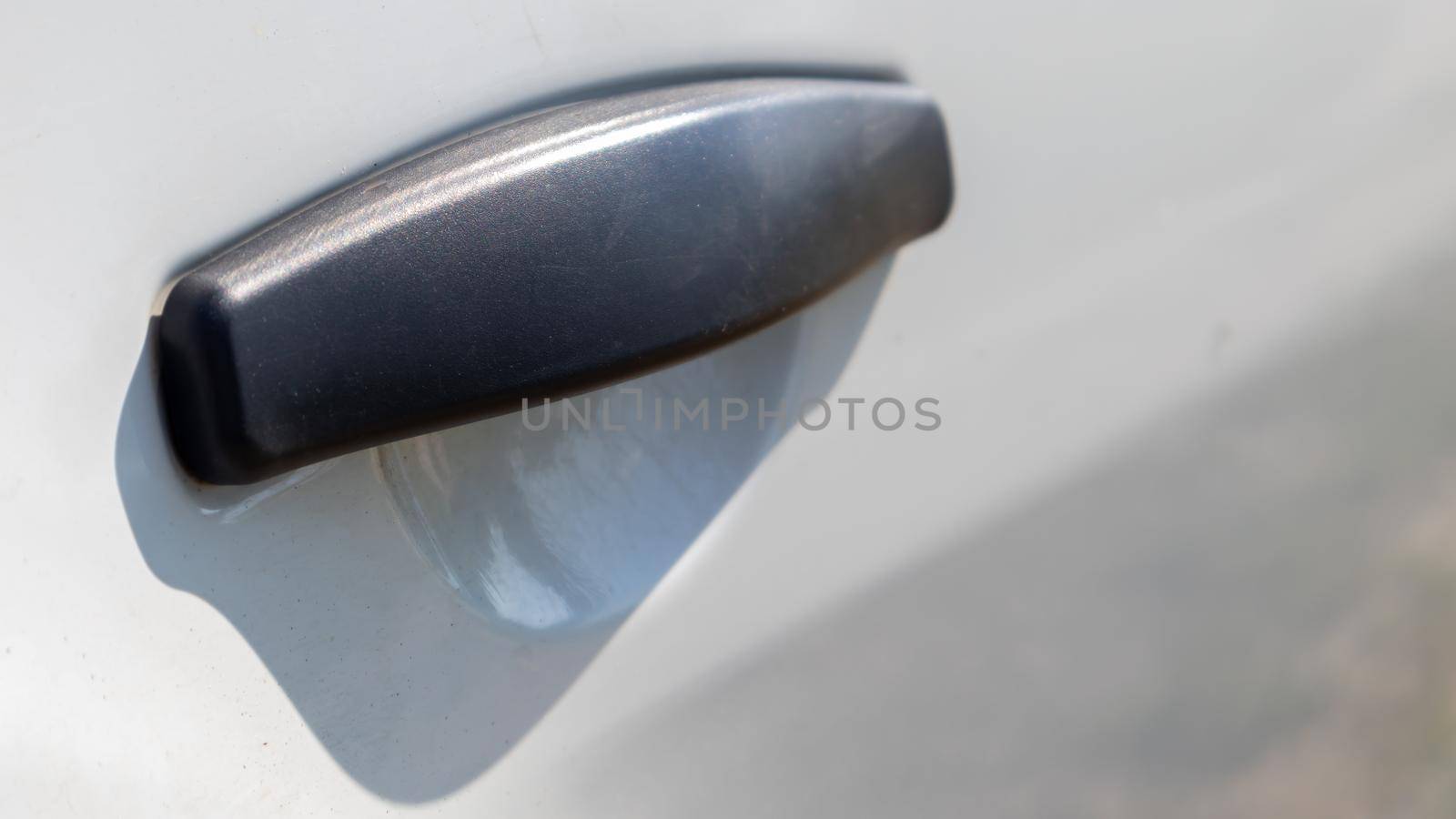 Black plastic door handle of a modern white car. Transport. Detail and part of the car. Door opening handle from outside