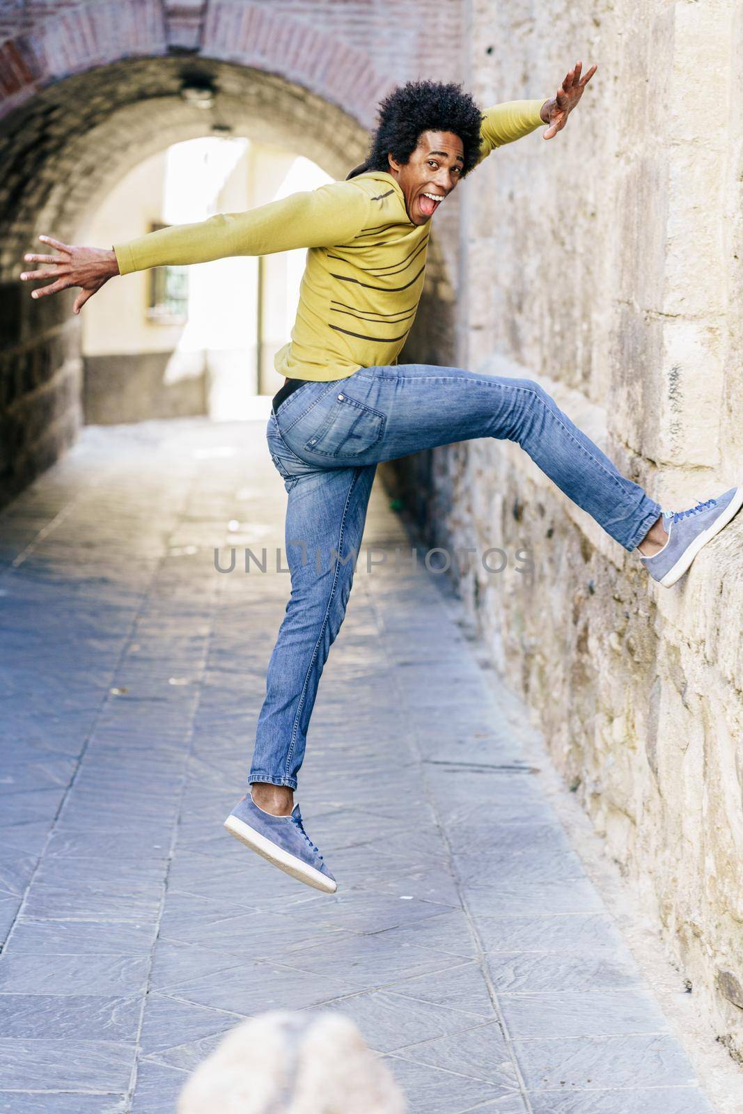 Black man with afro hair jumping for joy by javiindy