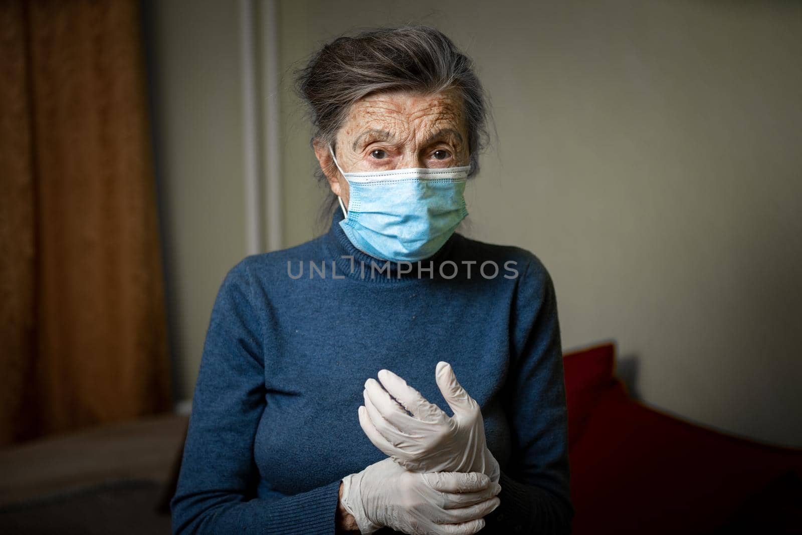 Portrait elderly woman took security measures, wearing gloves and medical mask, ahead of visit by social welfare workers during coronavirus quarantine. Lockdown and loneliness, need for care.