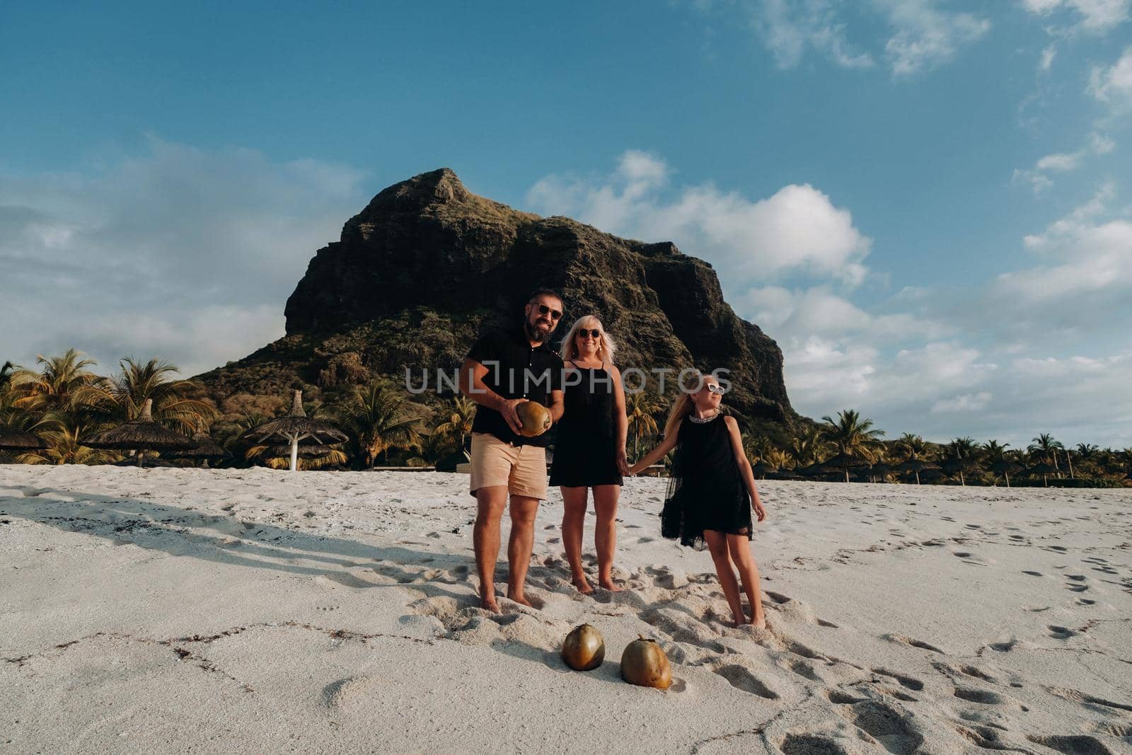 a family of three in black clothes on the white beach of Le Morne on the island of Mauritius