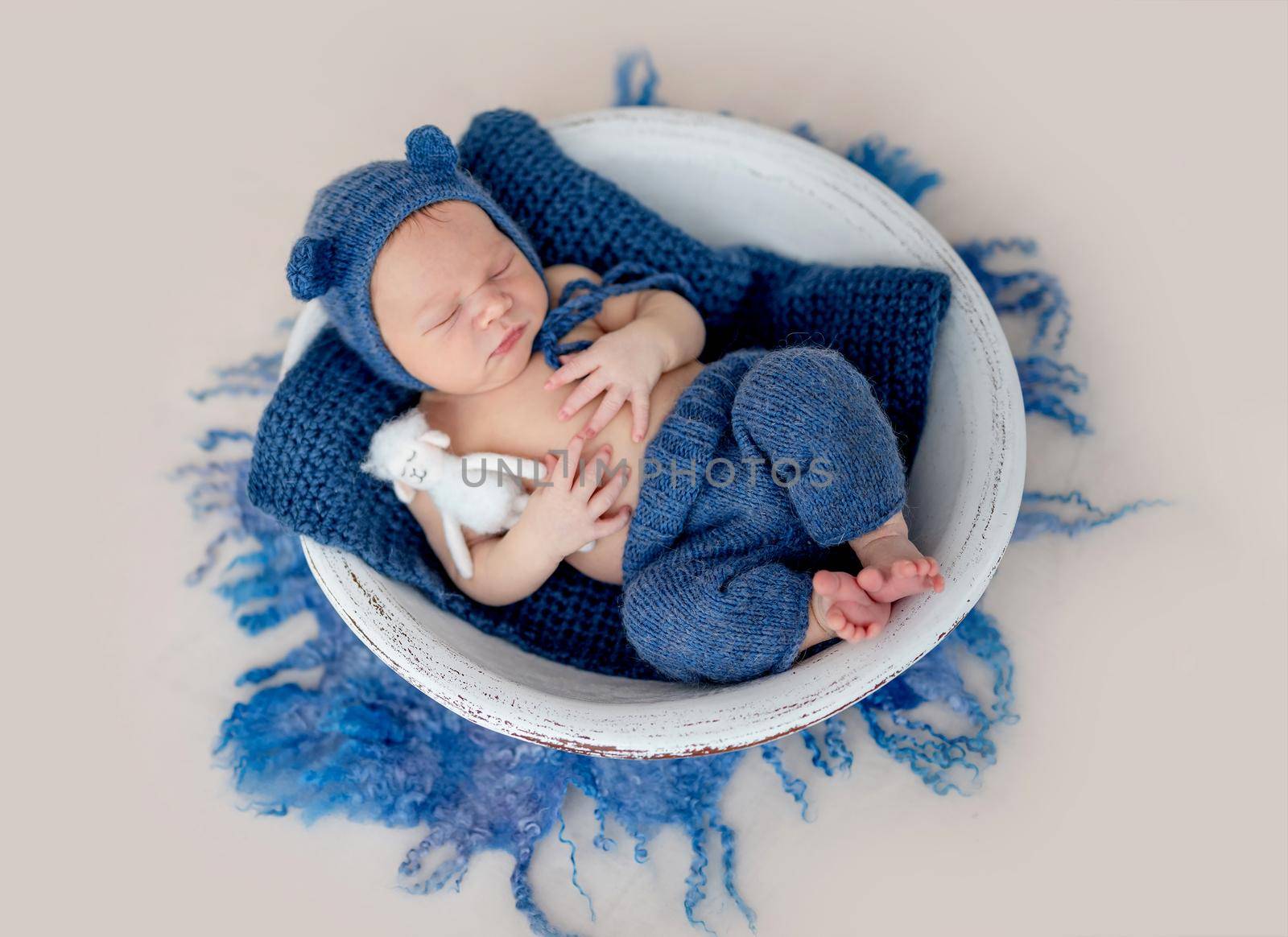 Adorable newborn boy and toy sleeping in cradle