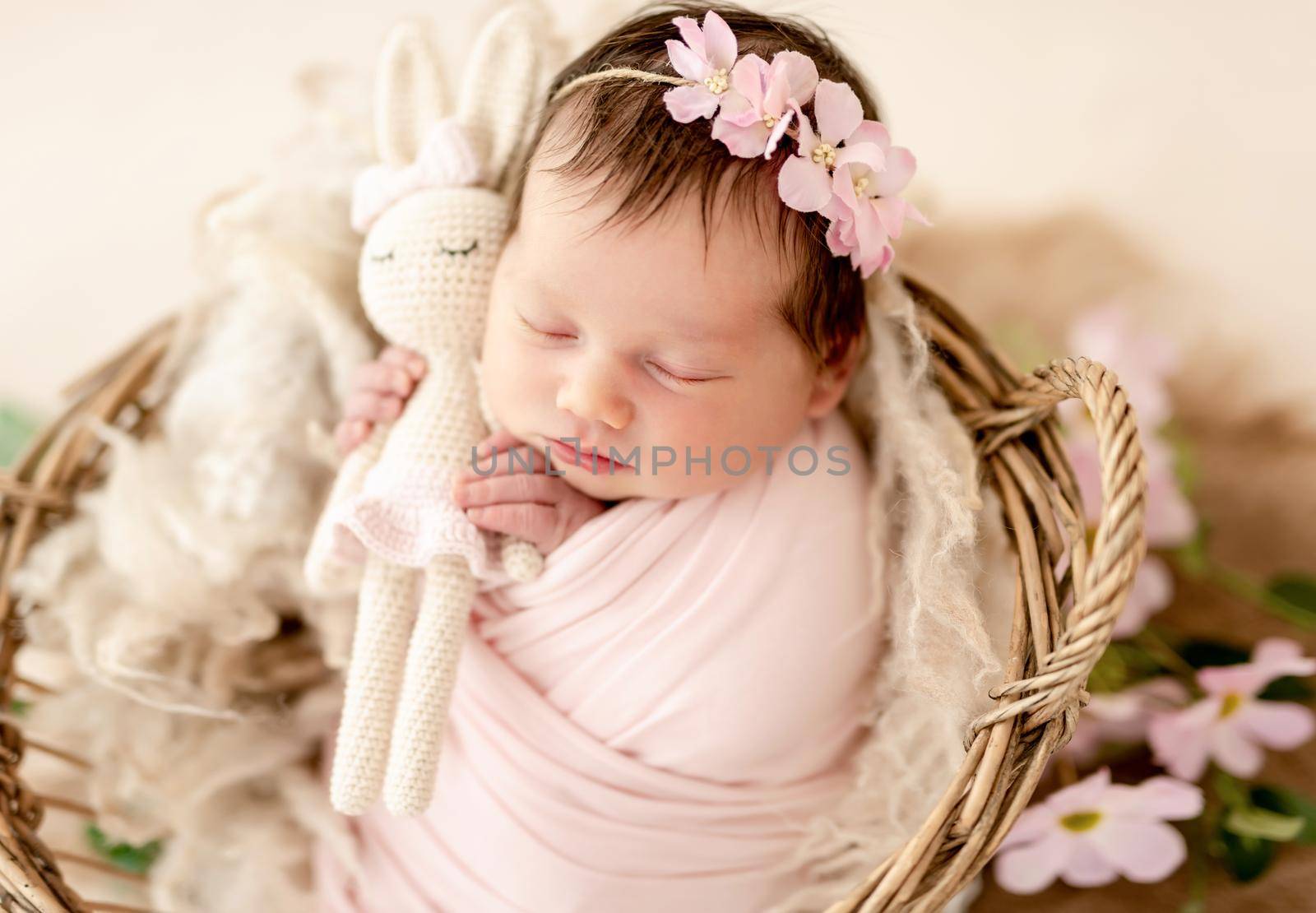 Lovely newborn in floral diadem holding toy