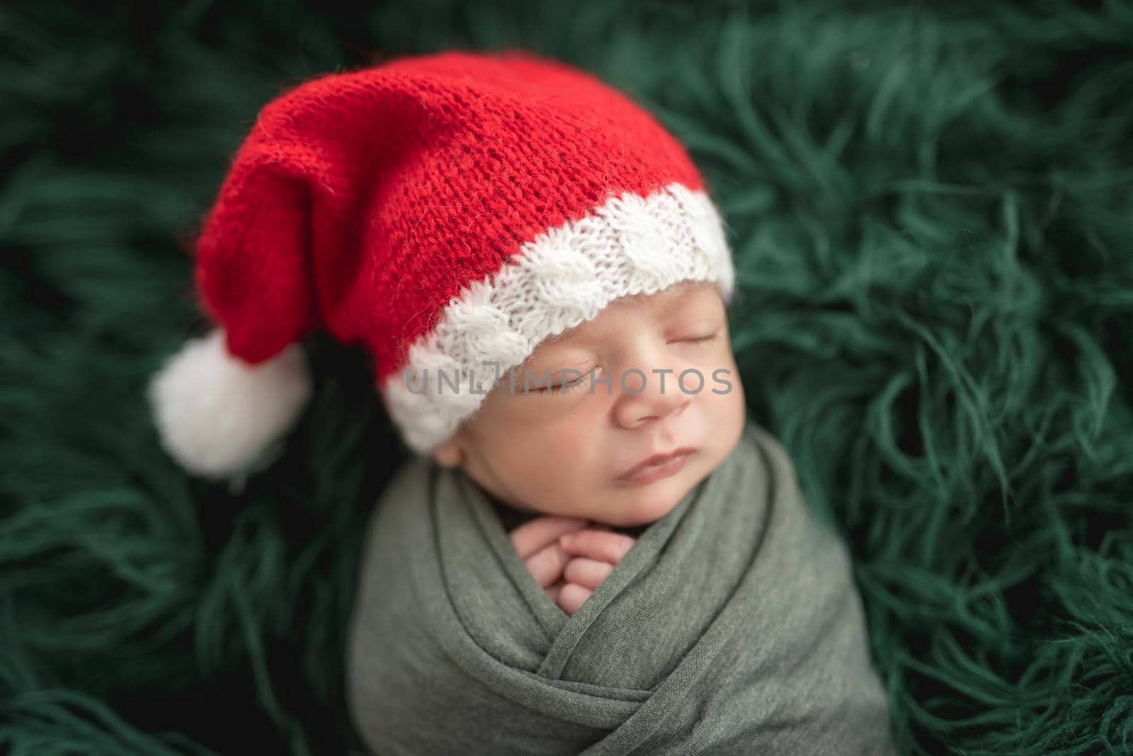 Adorable newborn in santa hat sleeping next to toy