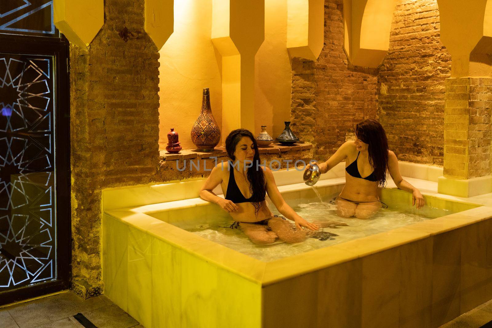 Two women enjoying Arabic baths Hammam in Granada, Andalusia, Spain. Elvira baths. Cold water pool