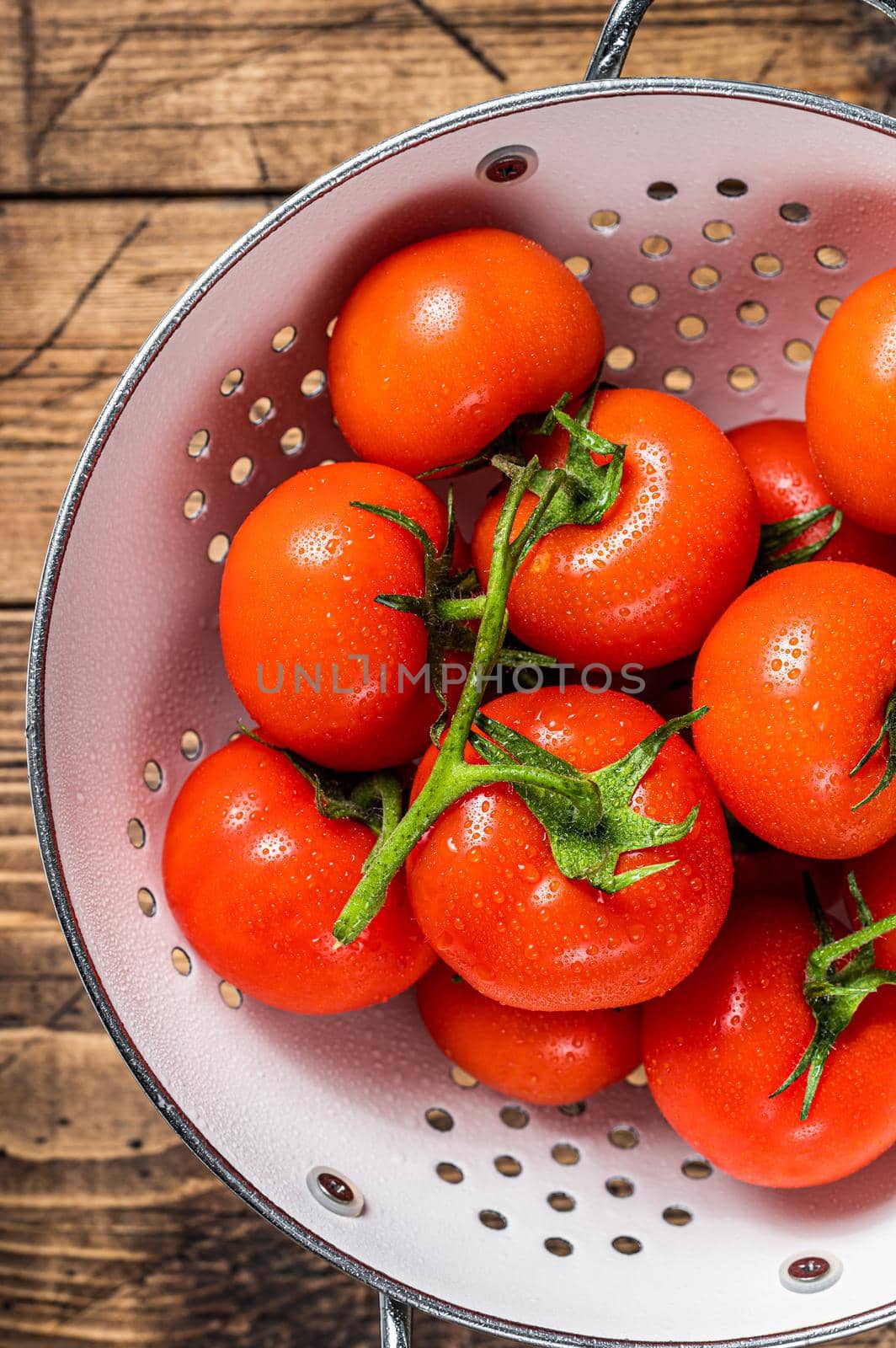 Branch of Red cherry tomatoes in colander. Wooden background. Top view.