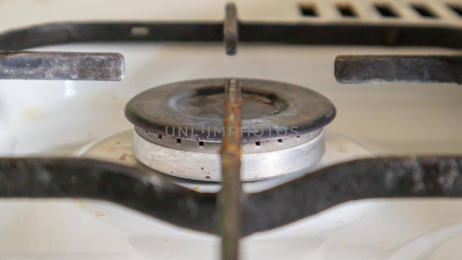 Dirty gas stove in the kitchen for cooking with vegetable oil stains and burnt food debris on the surface, close-up. Selective focus. Grease-covered gas hob in the kitchen