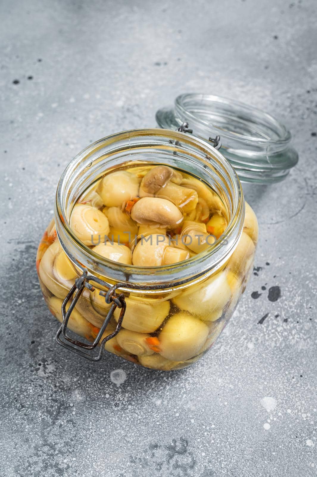 Pickled mushrooms champignons in a glass jar. Gray background. Top view by Composter