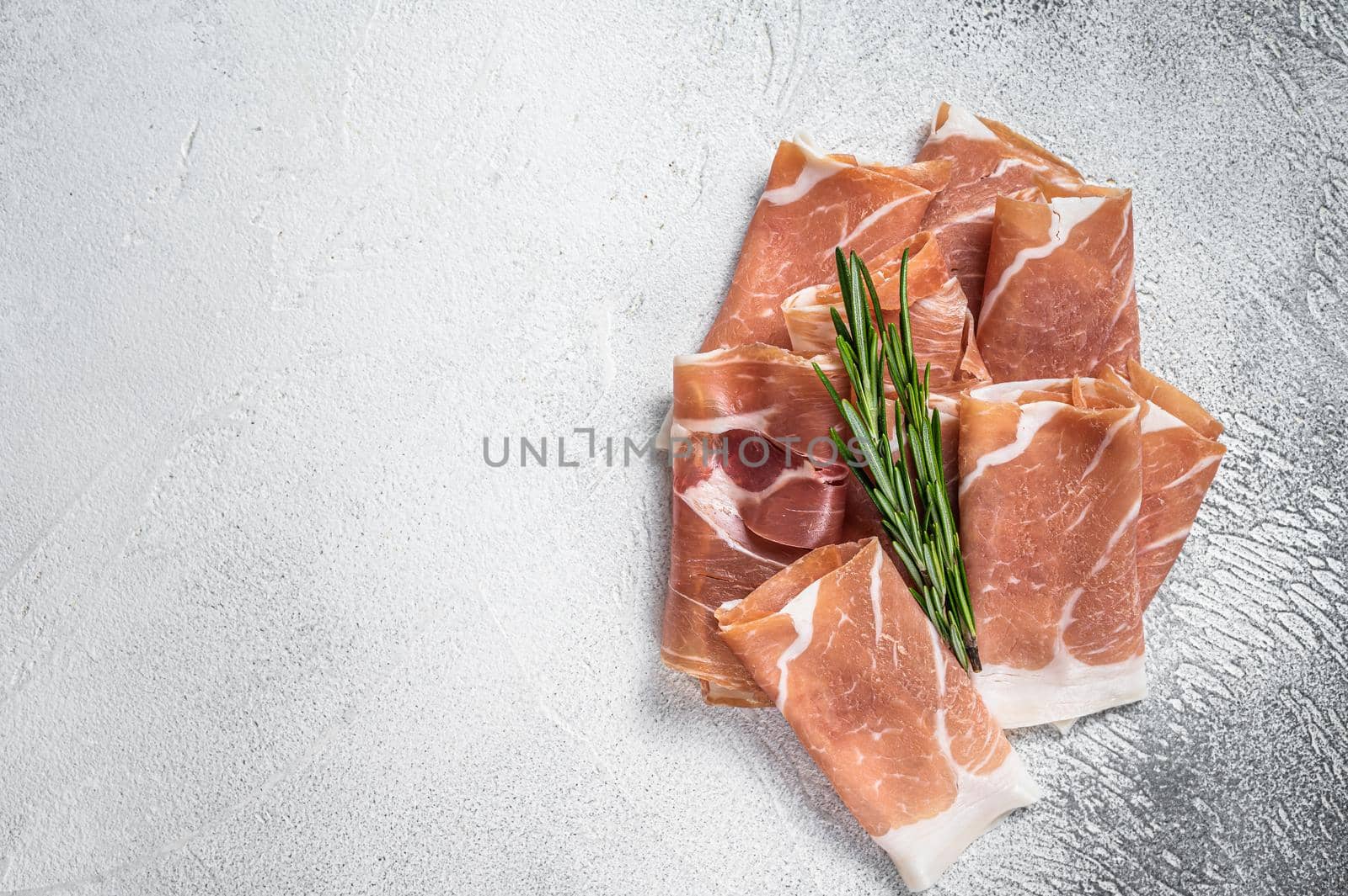 Italian prosciutto crudo parma ham on a table. White background. Top View. Copy space by Composter