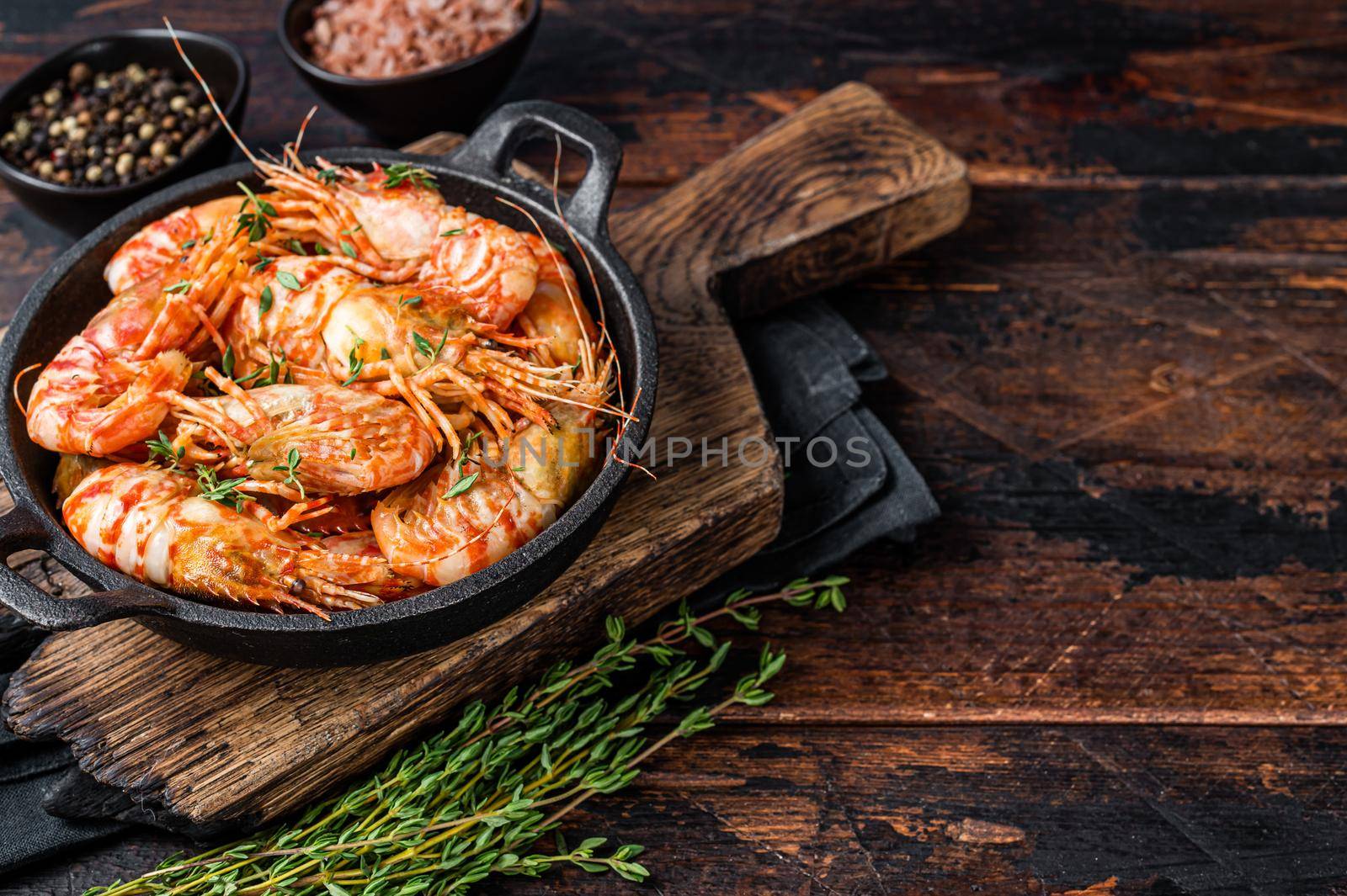 Cooking Greenland Shrimps Prawns in a pan with thyme and rosemary. Dark wooden background. Top view. Copy space by Composter