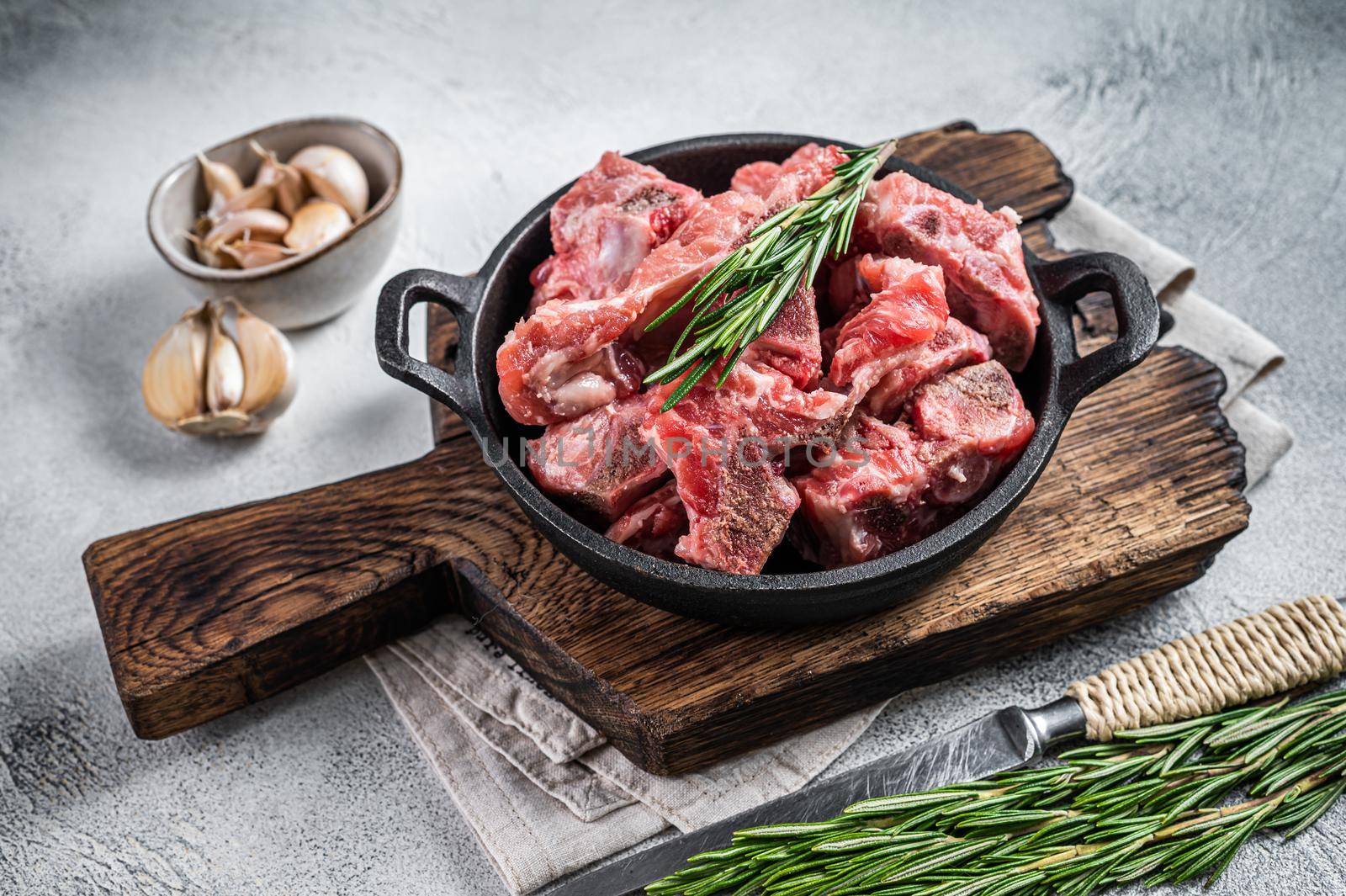 Raw diced meat cubes with bone in a pan. White background. Top View.