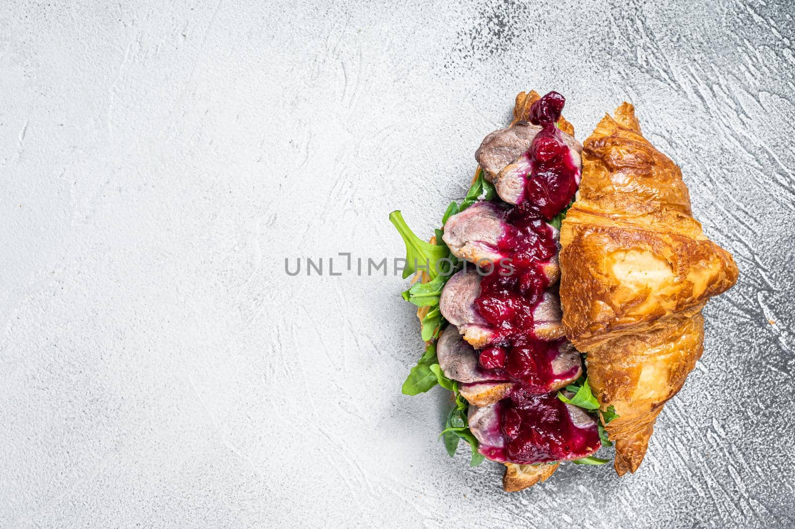 Duck breast Croissant sandwich with steak slices, arugula and sauce. White background. Top View. Copy space by Composter