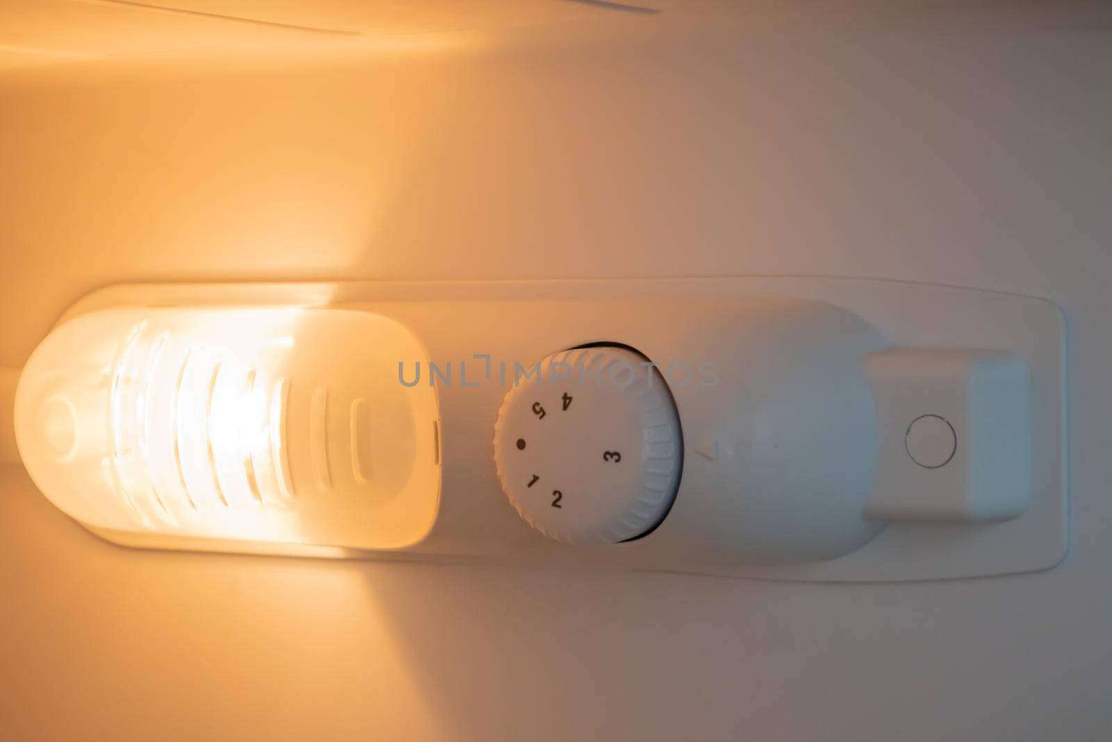 Orange light inside the refrigerator close-up. A lamp that turns on when the door is open to improve vision. Household appliances concept, changing the lamp in the freezer