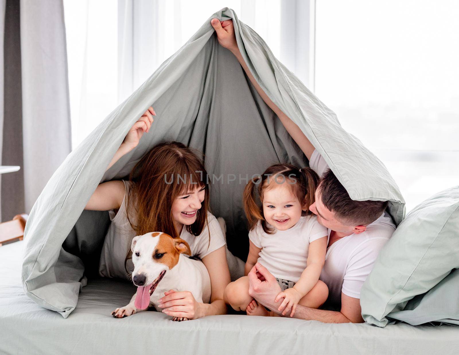Family under the blanket in the bed by tan4ikk1