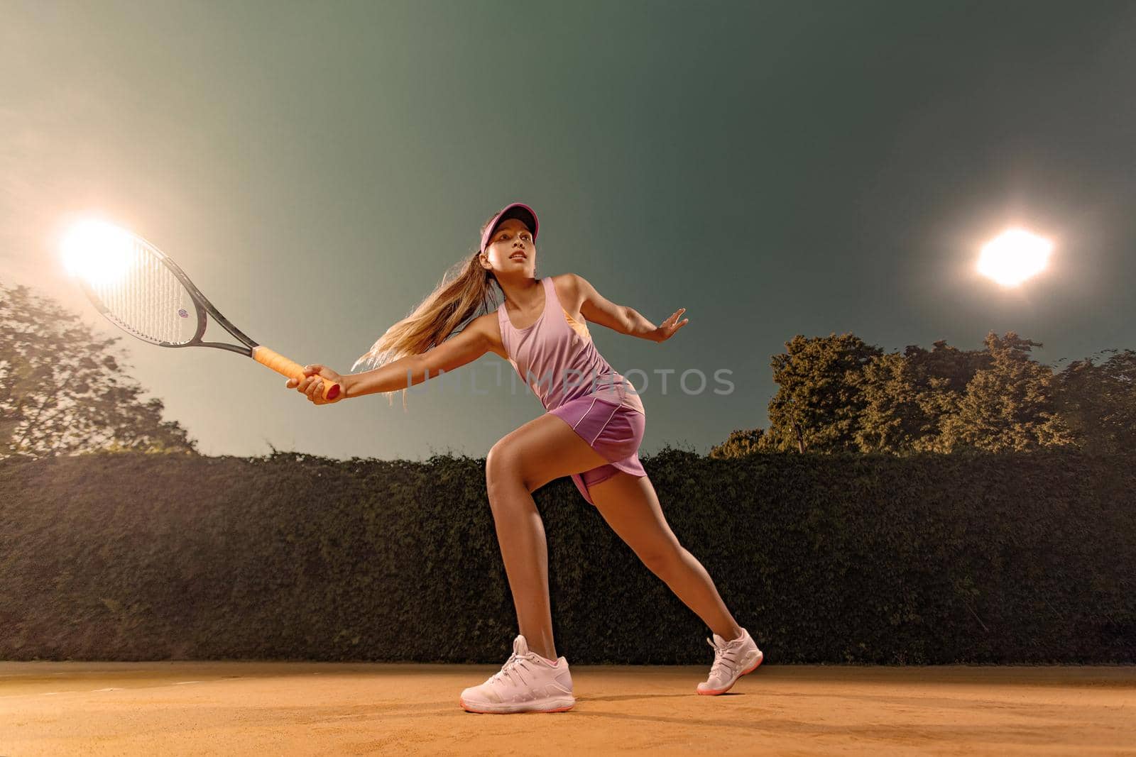 Beautiful girl tennis player with a racket on dark background wiht lights