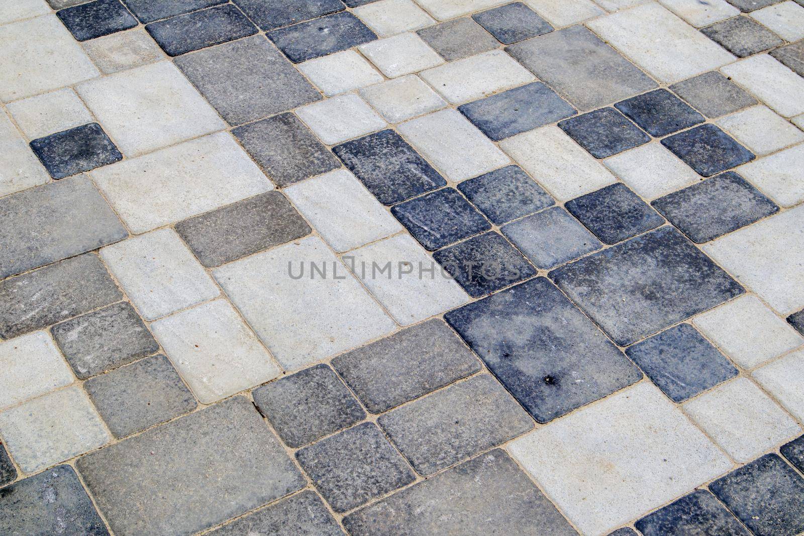 Concrete or paved newly laid gray paving slabs or stones for floors or walkways. Concrete paving slabs in the backyard or road paving. Garden brick path in the courtyard on a sandy foundation