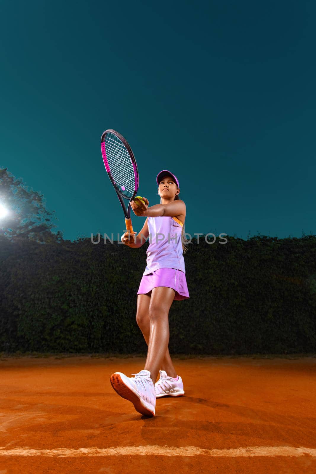 Tennis player. Beautiful girl teenager and athlete with racket in pink sporswear and hat on tennis court. Fashion and sport concept. by MikeOrlov