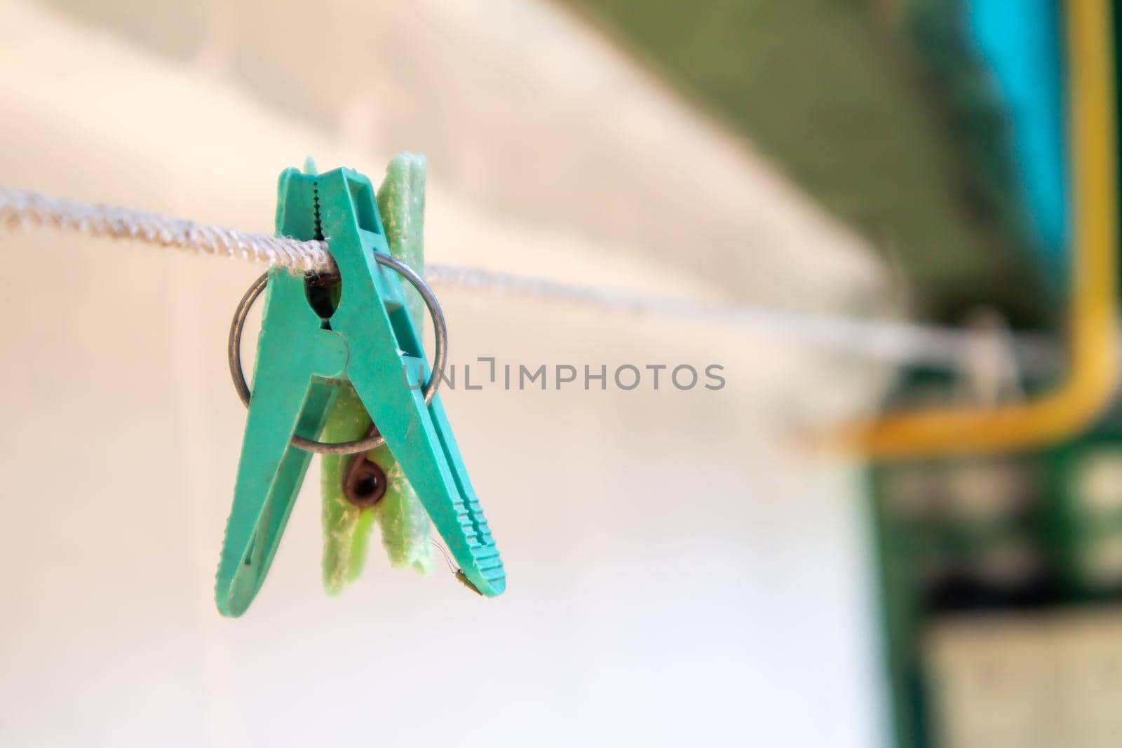 Plastic clothespins hang in a row on the rope. Rope outdoors, on a blurred background in a sunny garden. Clothesline on the street. Clothespins