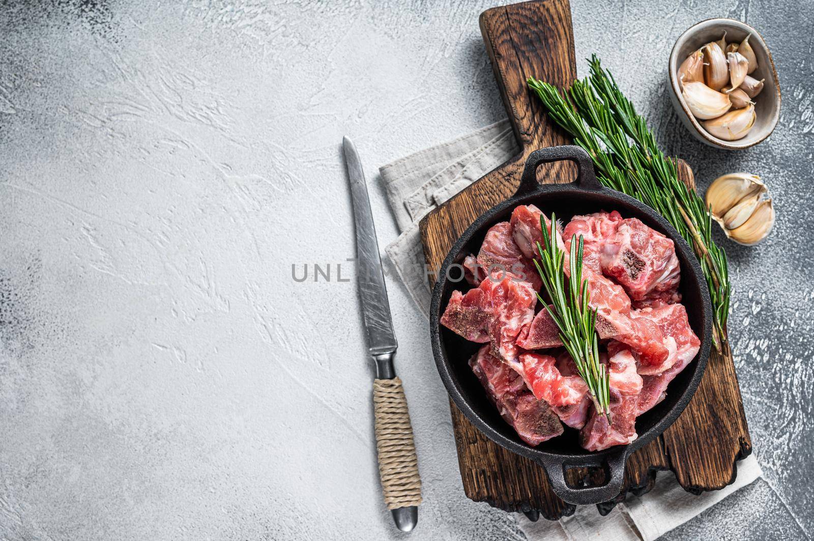 Raw diced meat cubes with bone in a pan. White background. Top View. Copy space by Composter