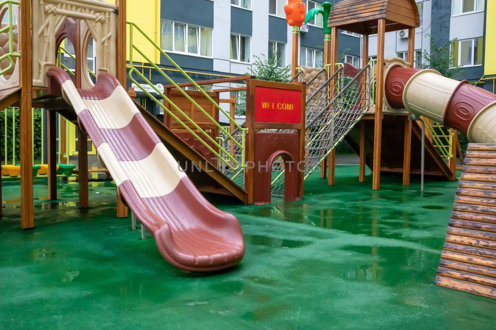 The courtyard of a high-rise building with a modern large playground made of wood and plastic on a rainy summer day without people. Ukraine, Kiev - August 19, 2021