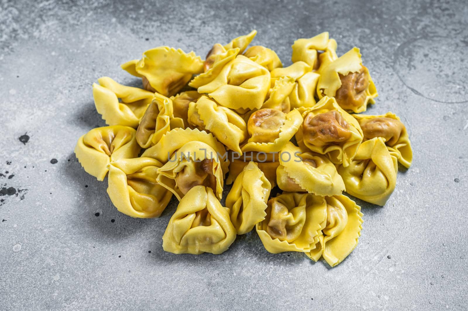 Uncooked raw ravioli with Mozzarella and Tomato. Gray background. Top view.